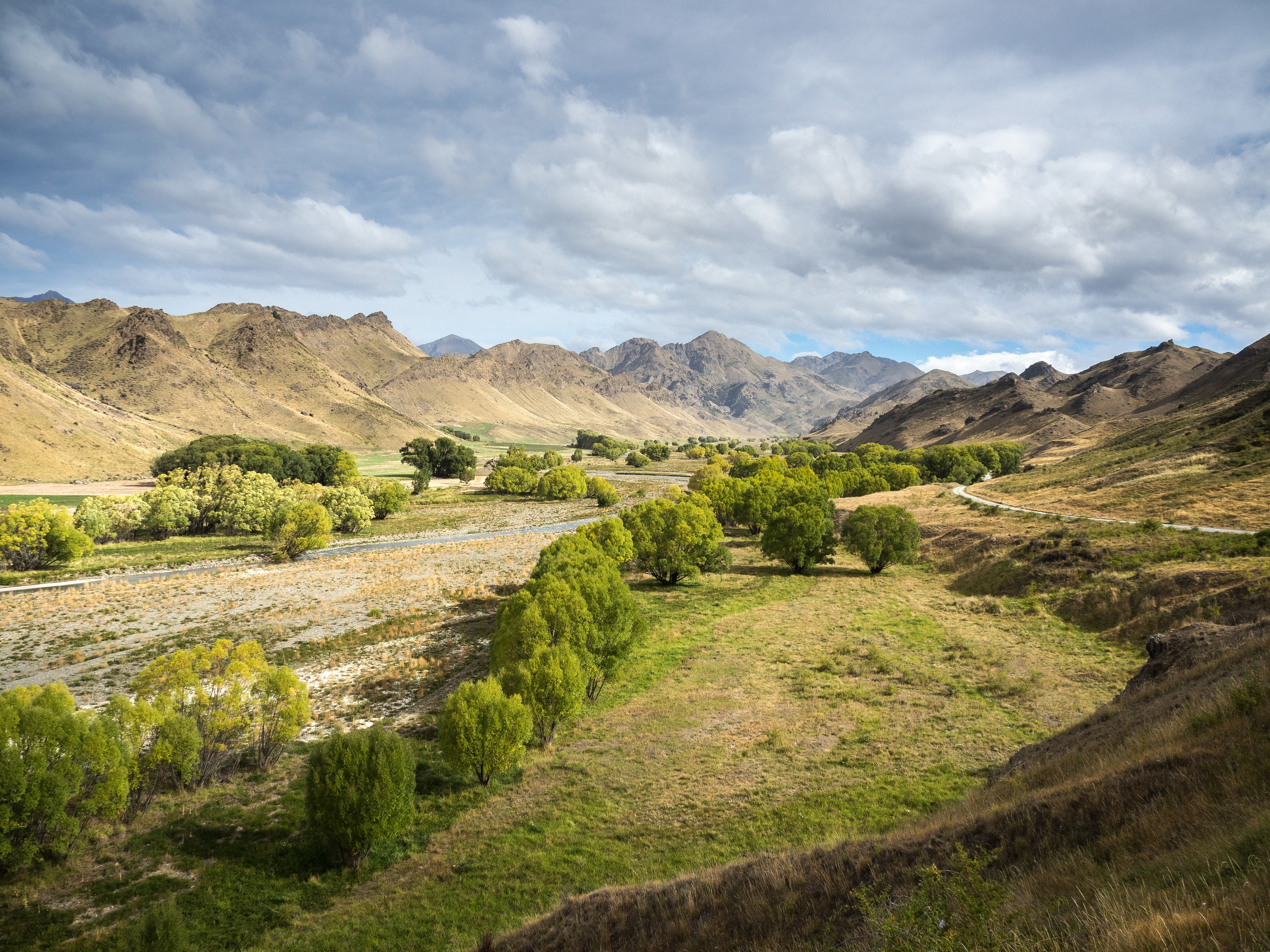 Valley with hills, trees, and road in New Zealand HD Wallpaper