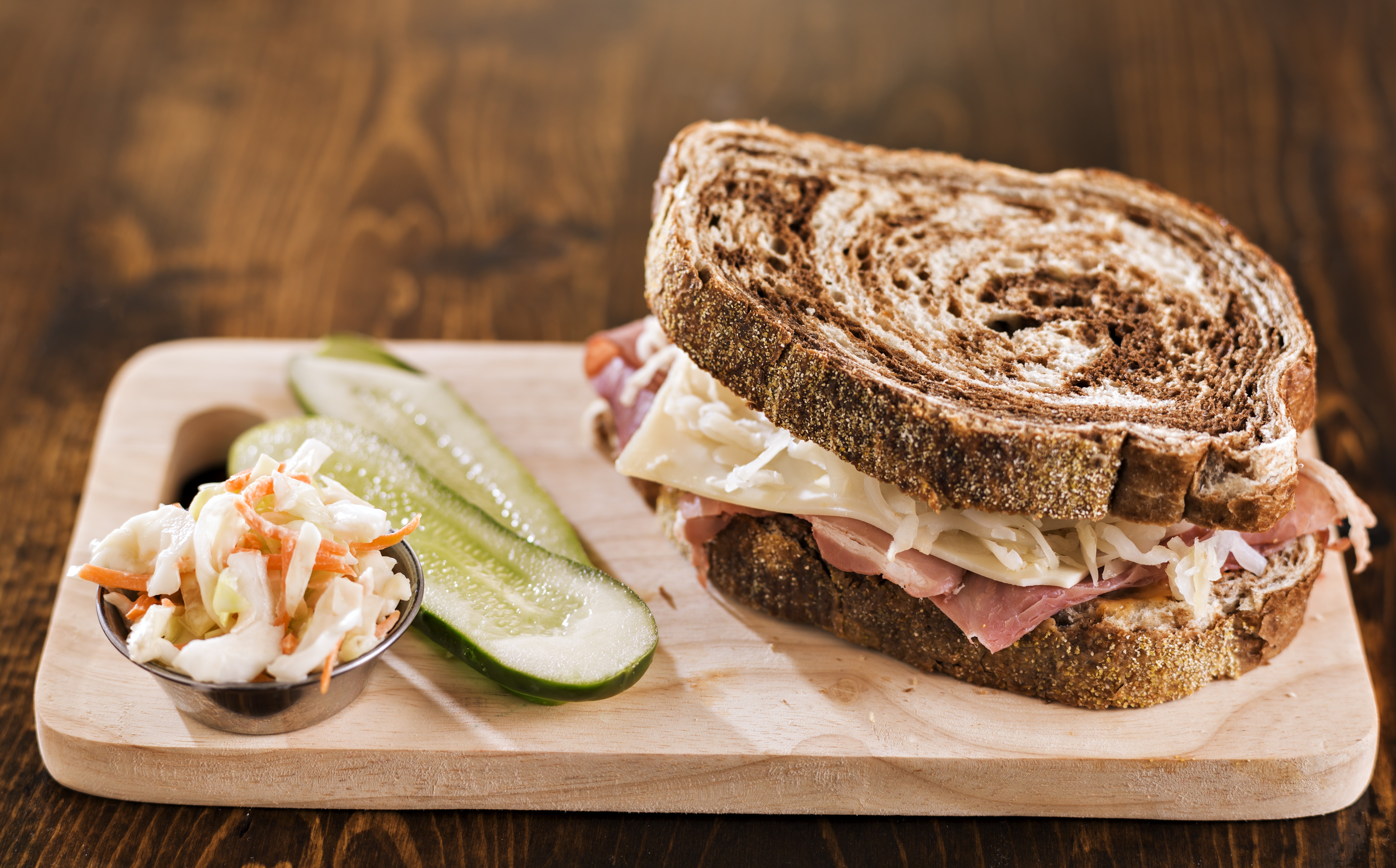 Sandwich with coleslaw and pickles on a cutting board HD Wallpaper
