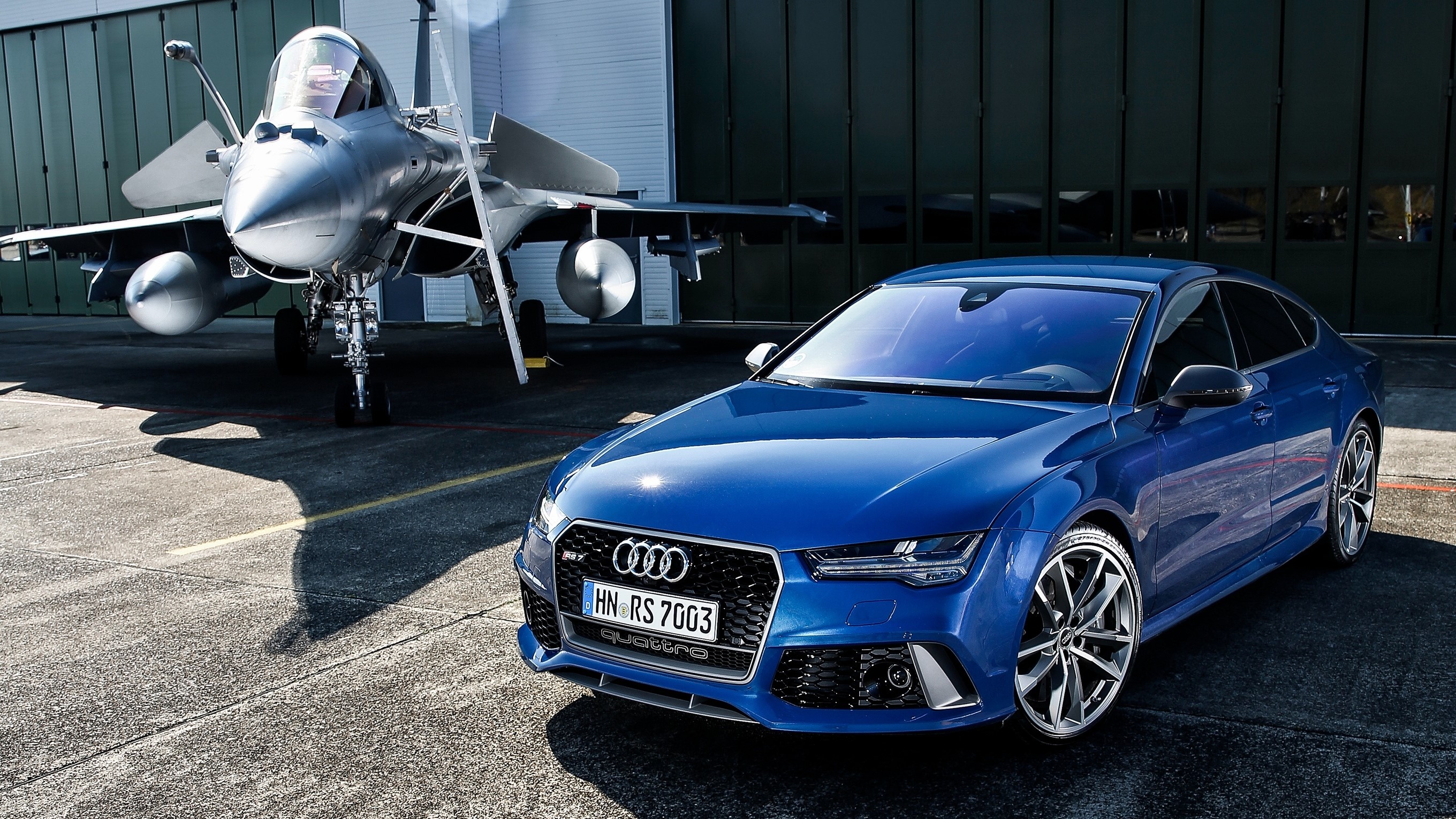 Blue Audi RS 7 Sportback next to a fighter jet HD Wallpaper