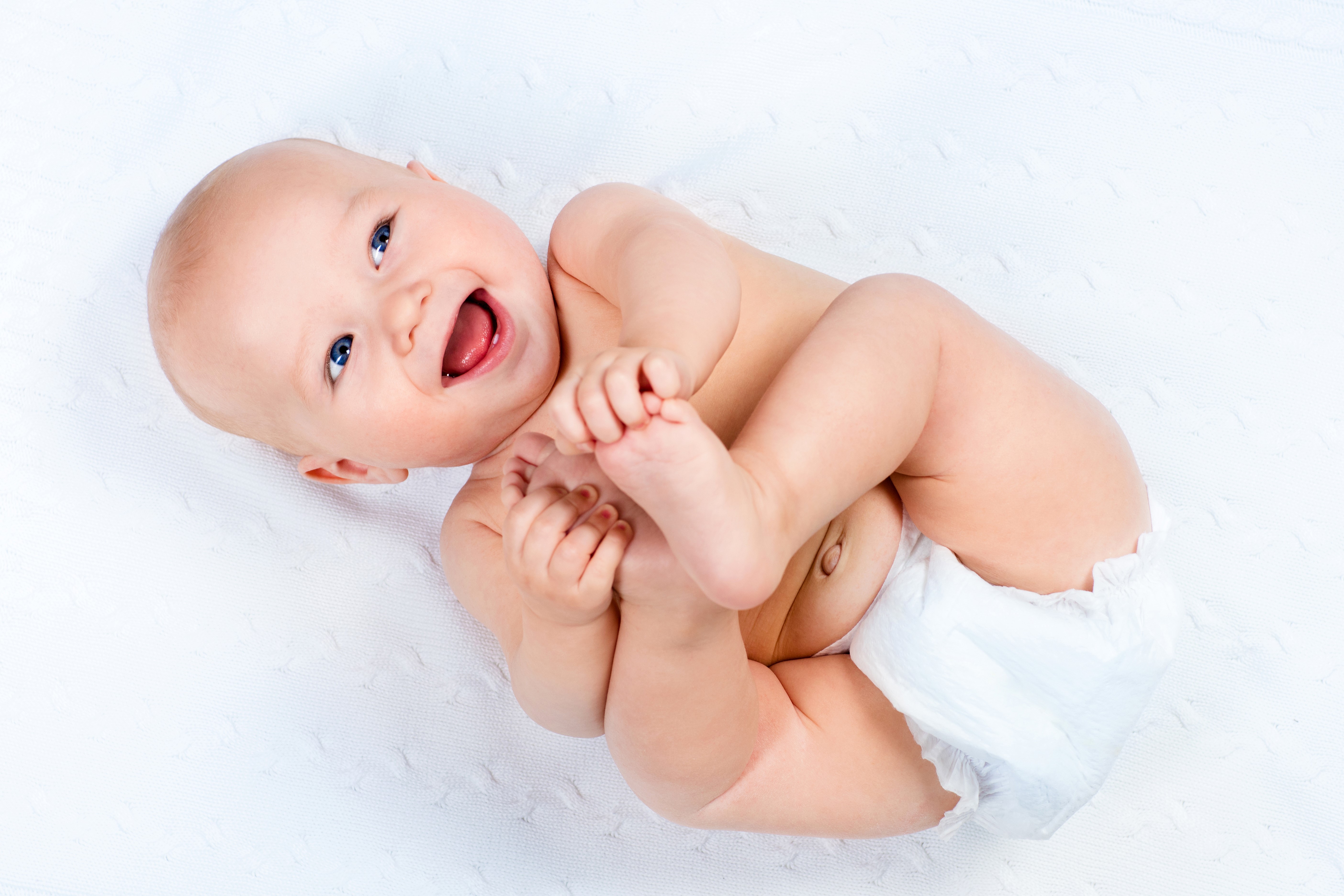Baby smiling and playing with legs HD Wallpaper