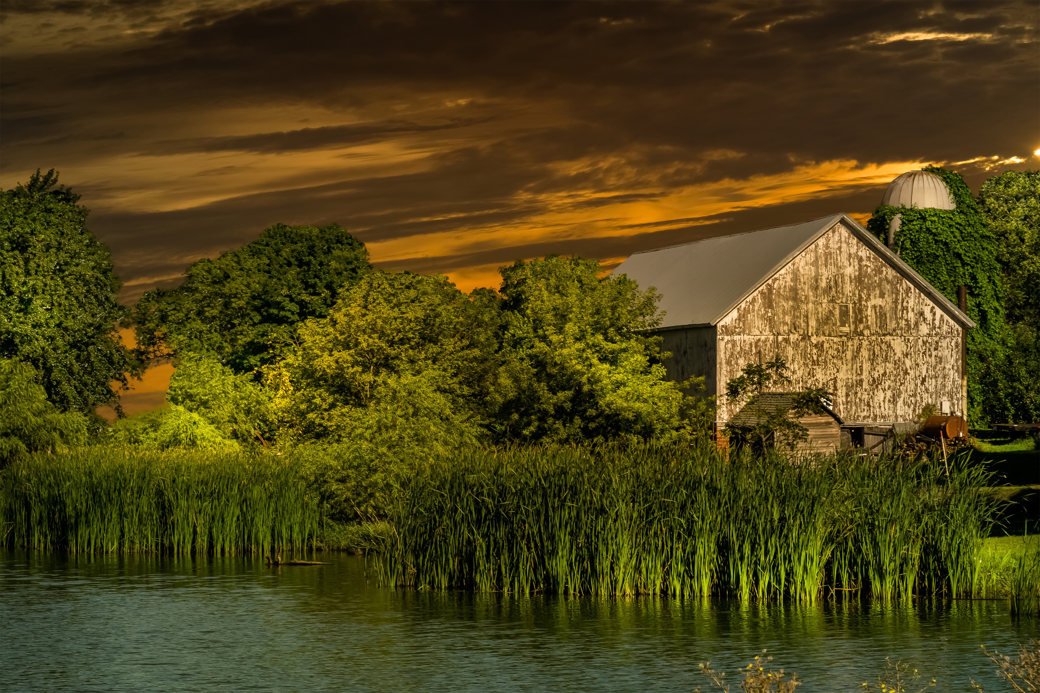 Barn and silo by a pond at sunset HD Wallpaper