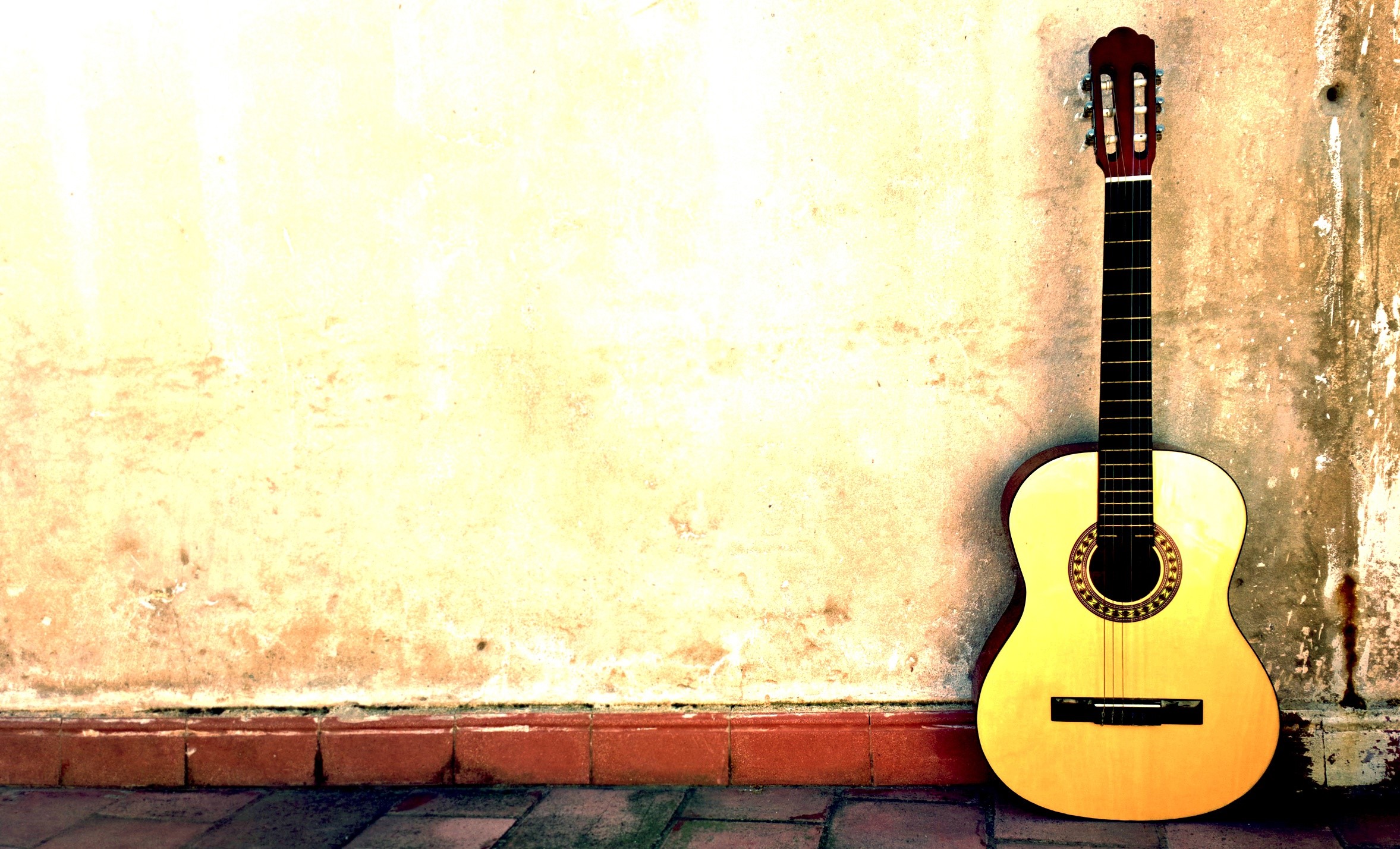 Acoustic guitar leaning against a textured wall HD Wallpaper