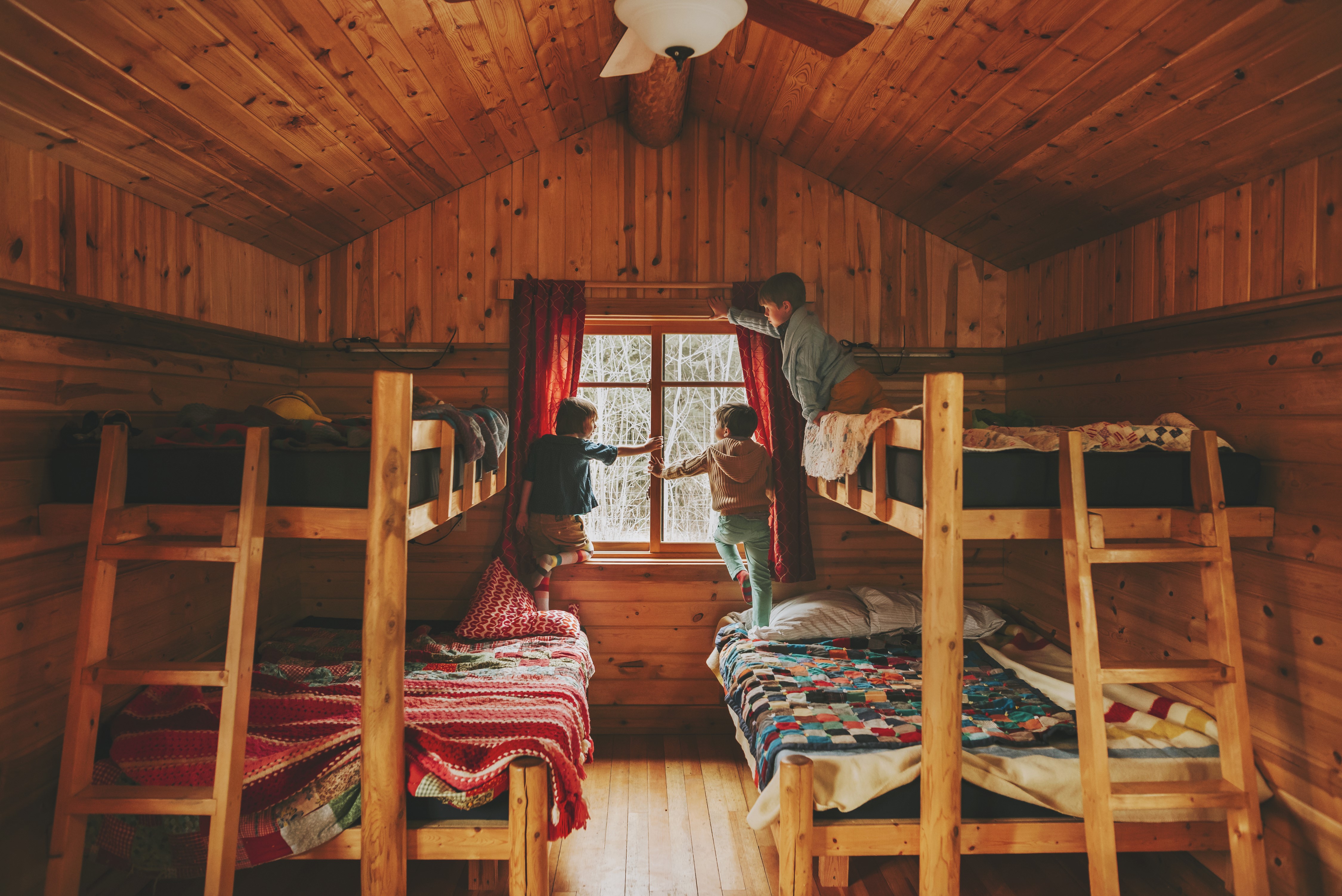 Three boys in a wooden cabin looking out a window HD Wallpaper