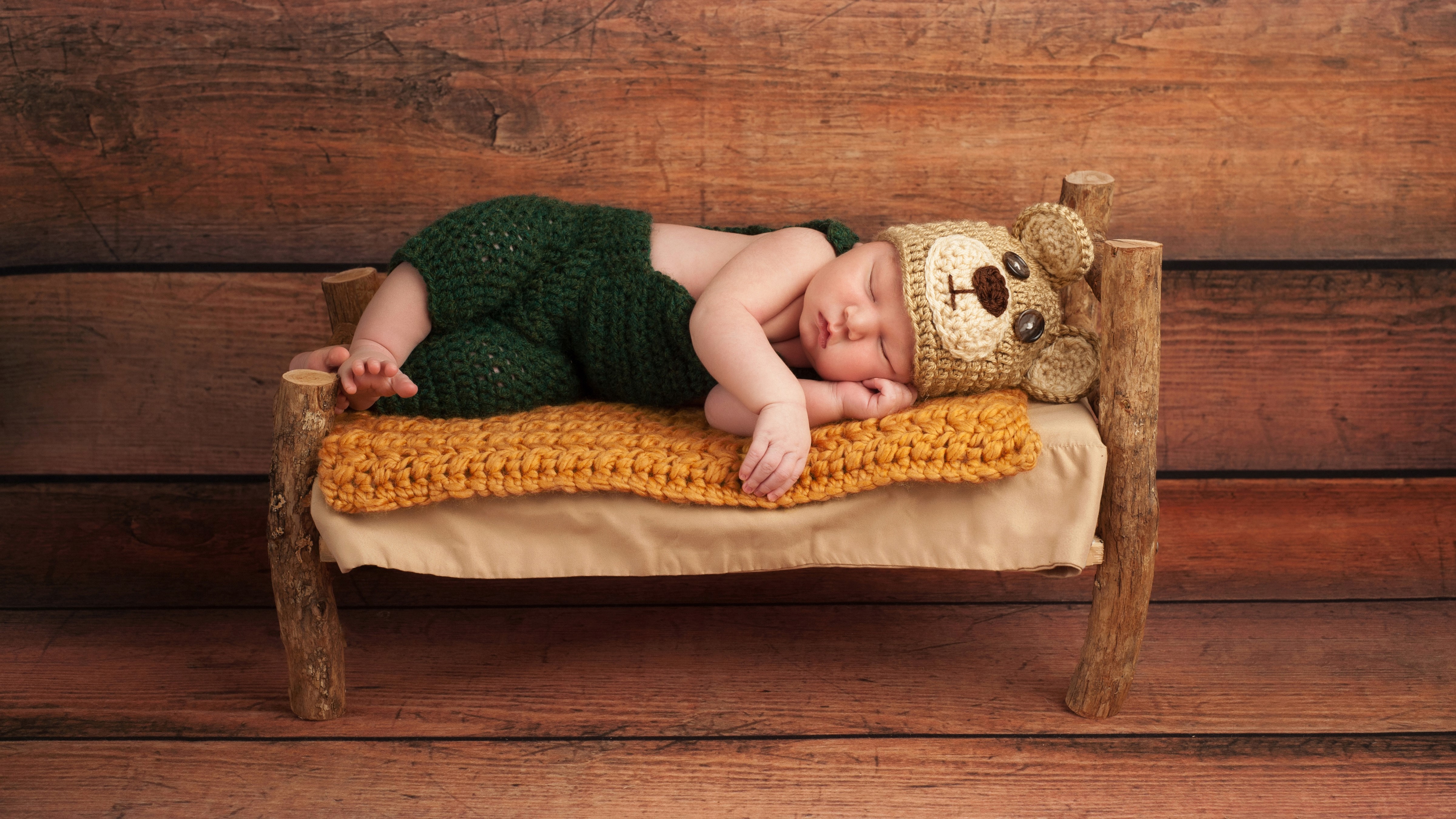 Infant sleeping on a bed wearing a bear hat HD Wallpaper