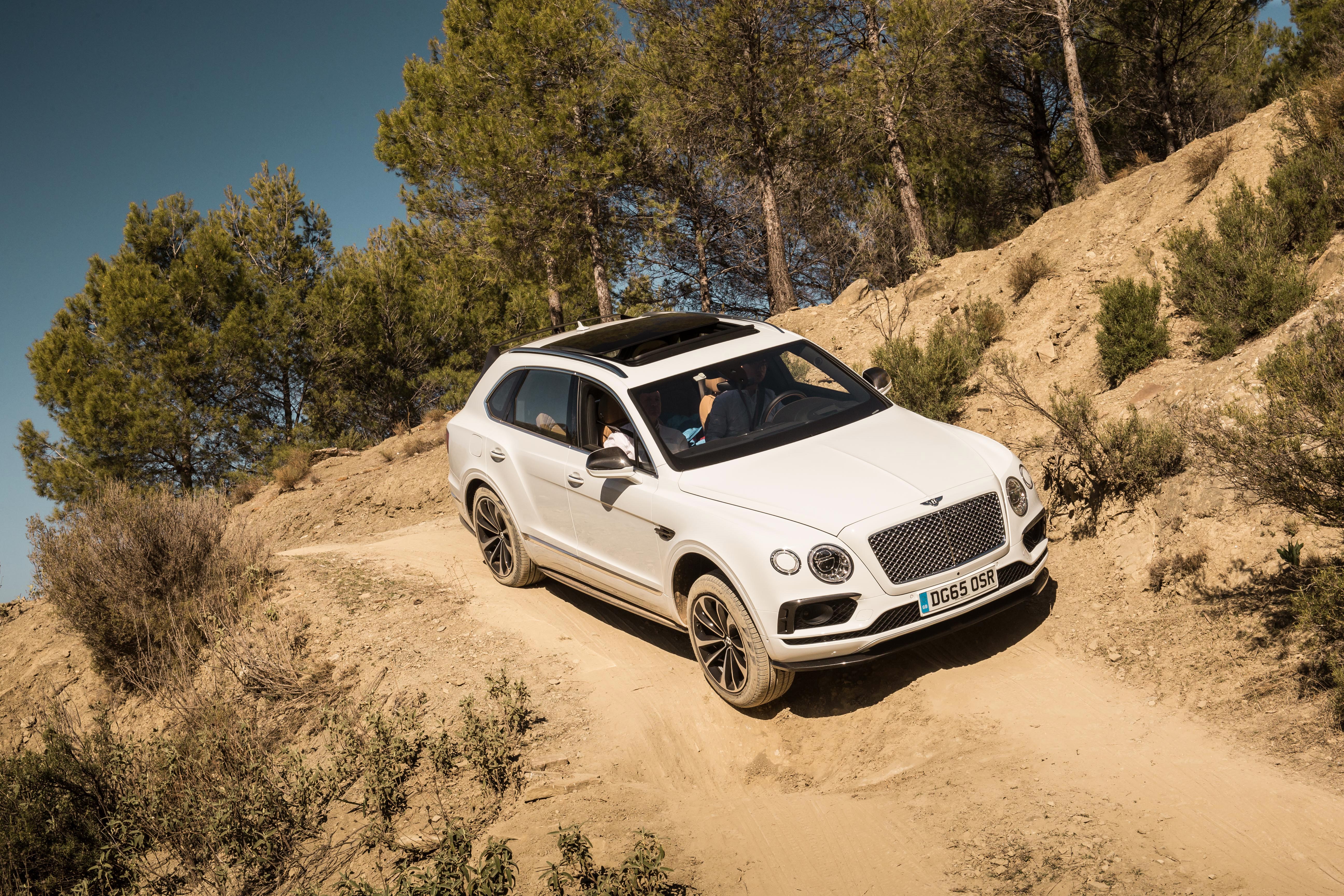 White Bentley Bentayga driving on a dirt road HD Wallpaper