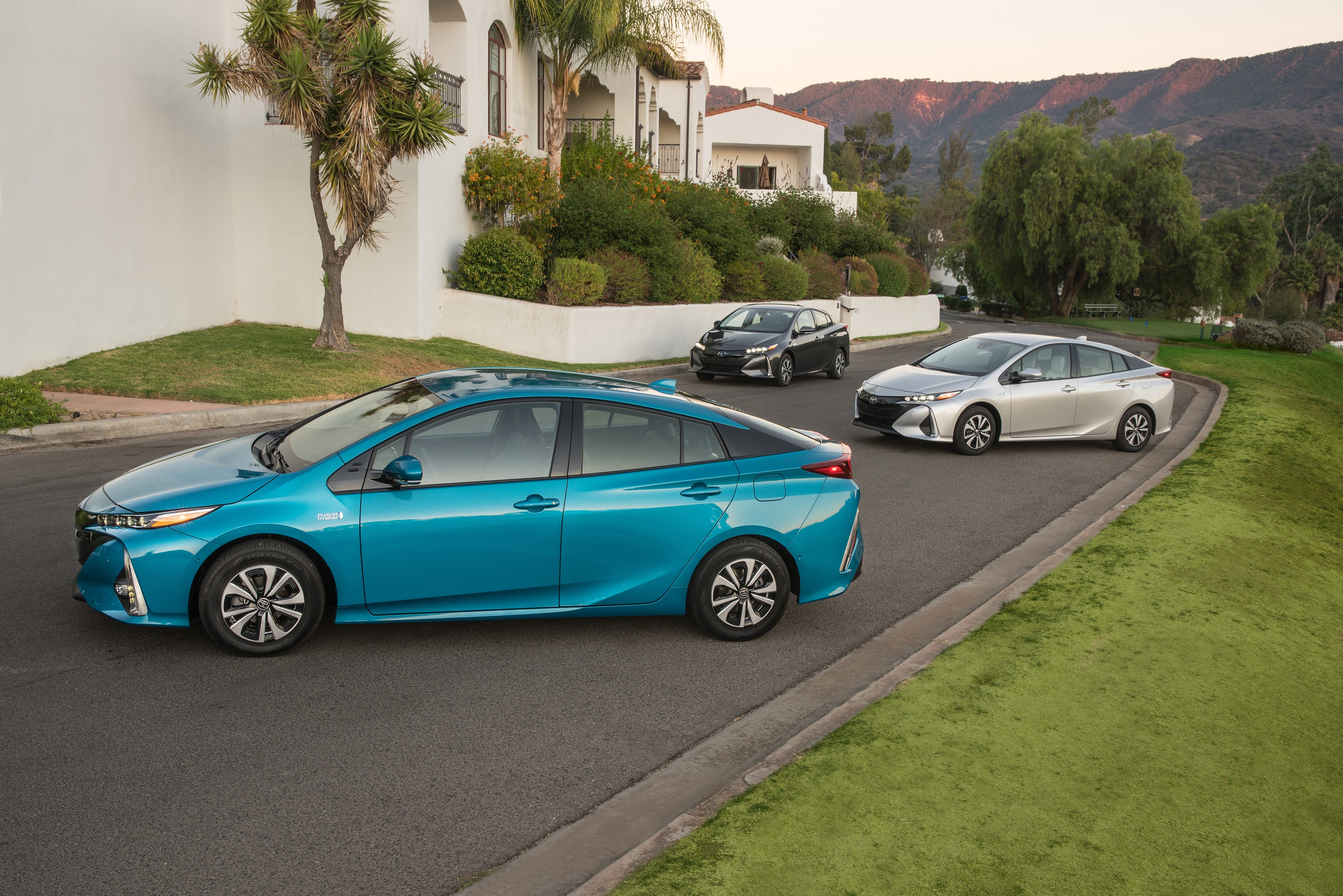 Three Toyota Prius cars on a suburban street HD Wallpaper