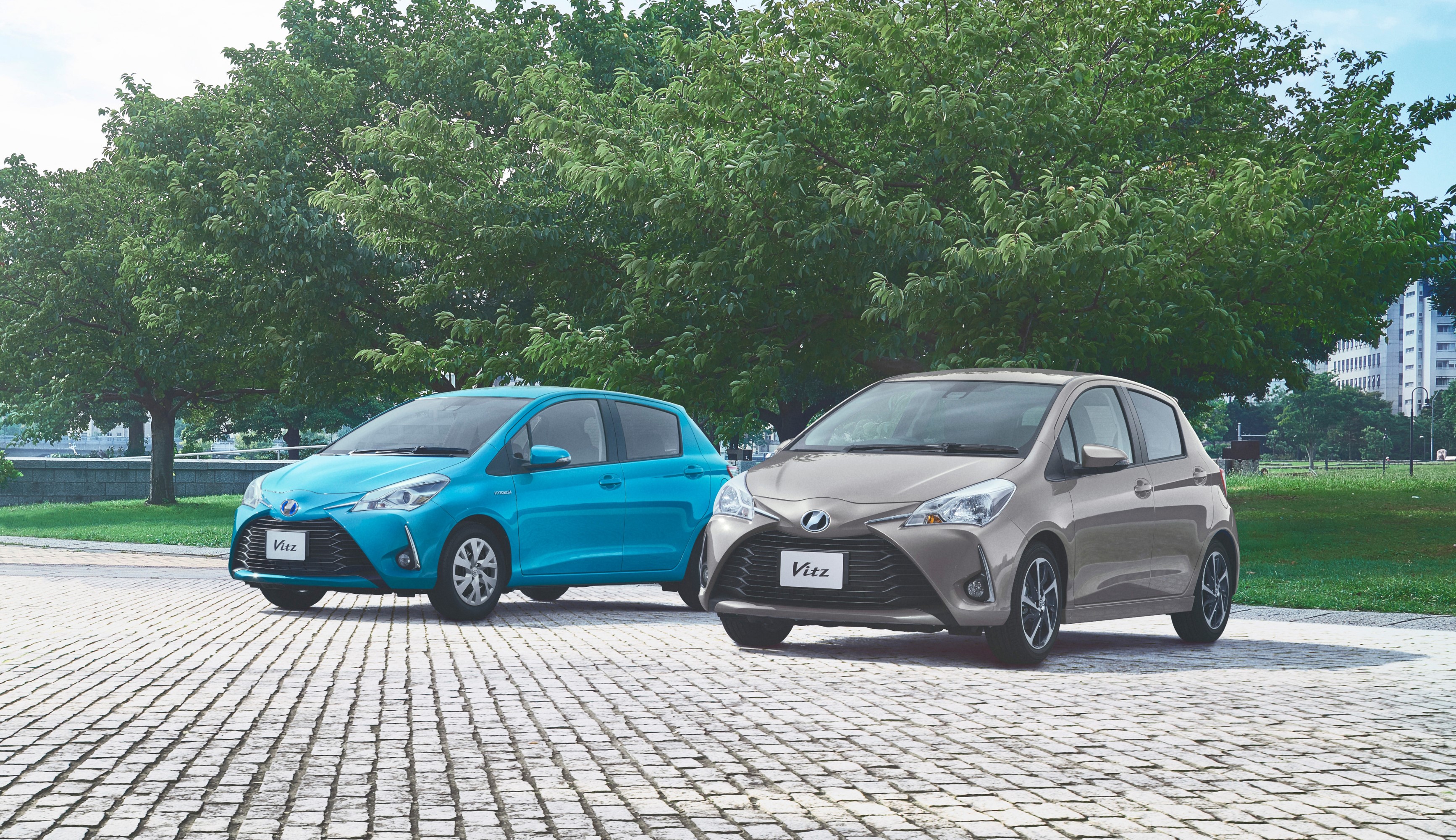 Two Toyota Vitz cars parked on a cobblestone path HD Wallpaper
