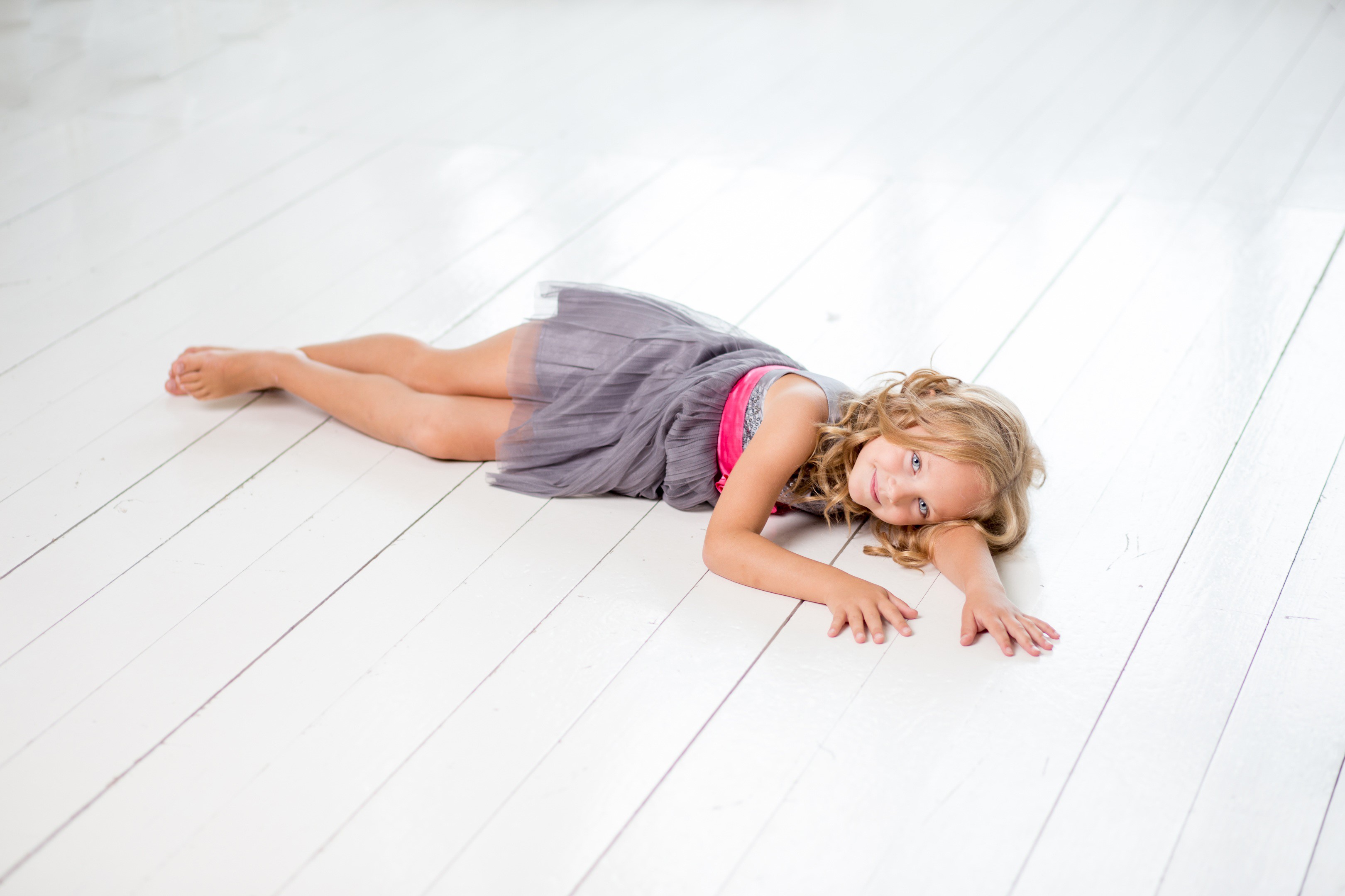 Young girl in a dress lying on a wooden floor HD Wallpaper