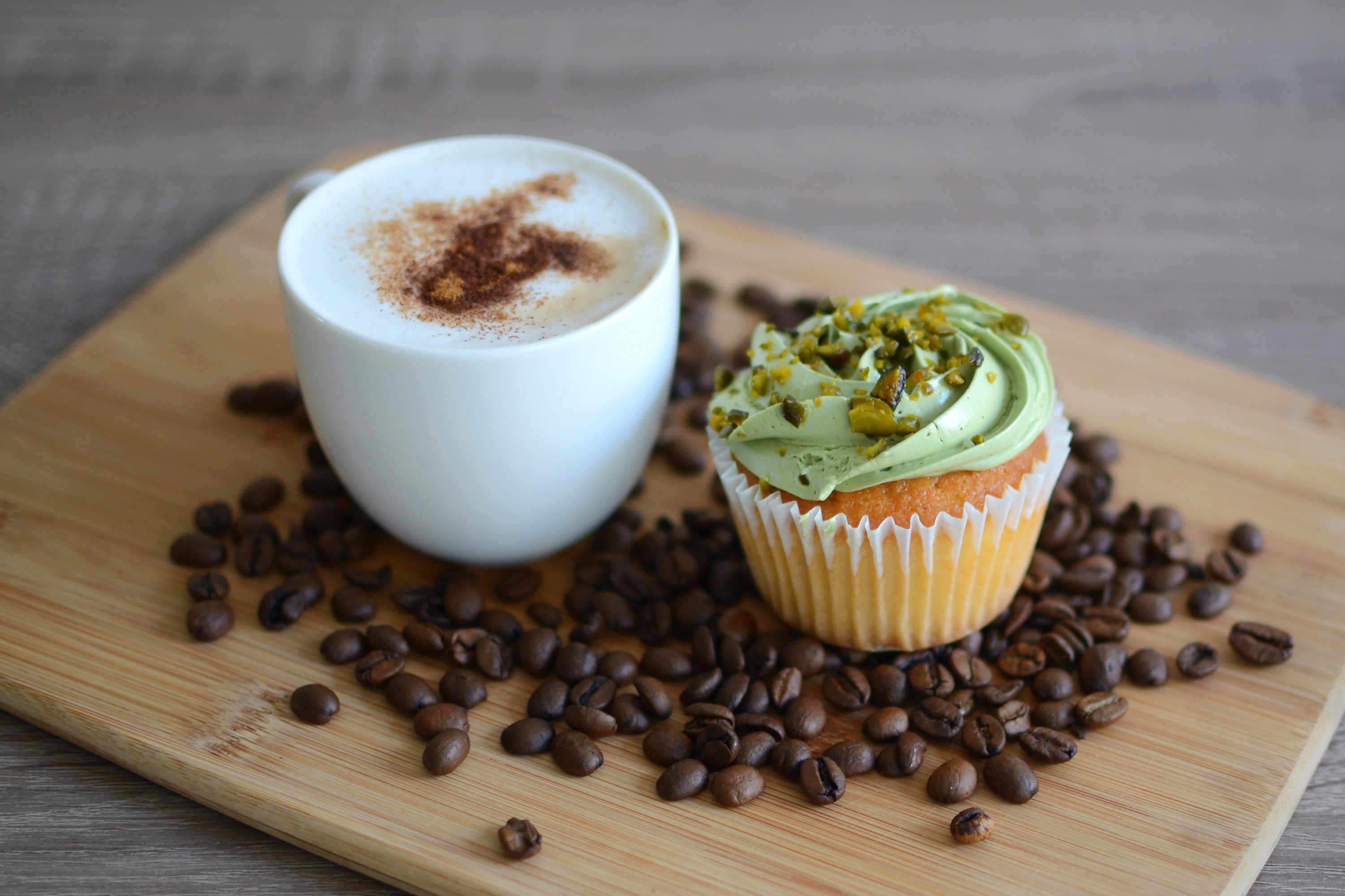 Cappuccino and pistachio cupcake on a cutting board with coffee beans HD Wallpaper
