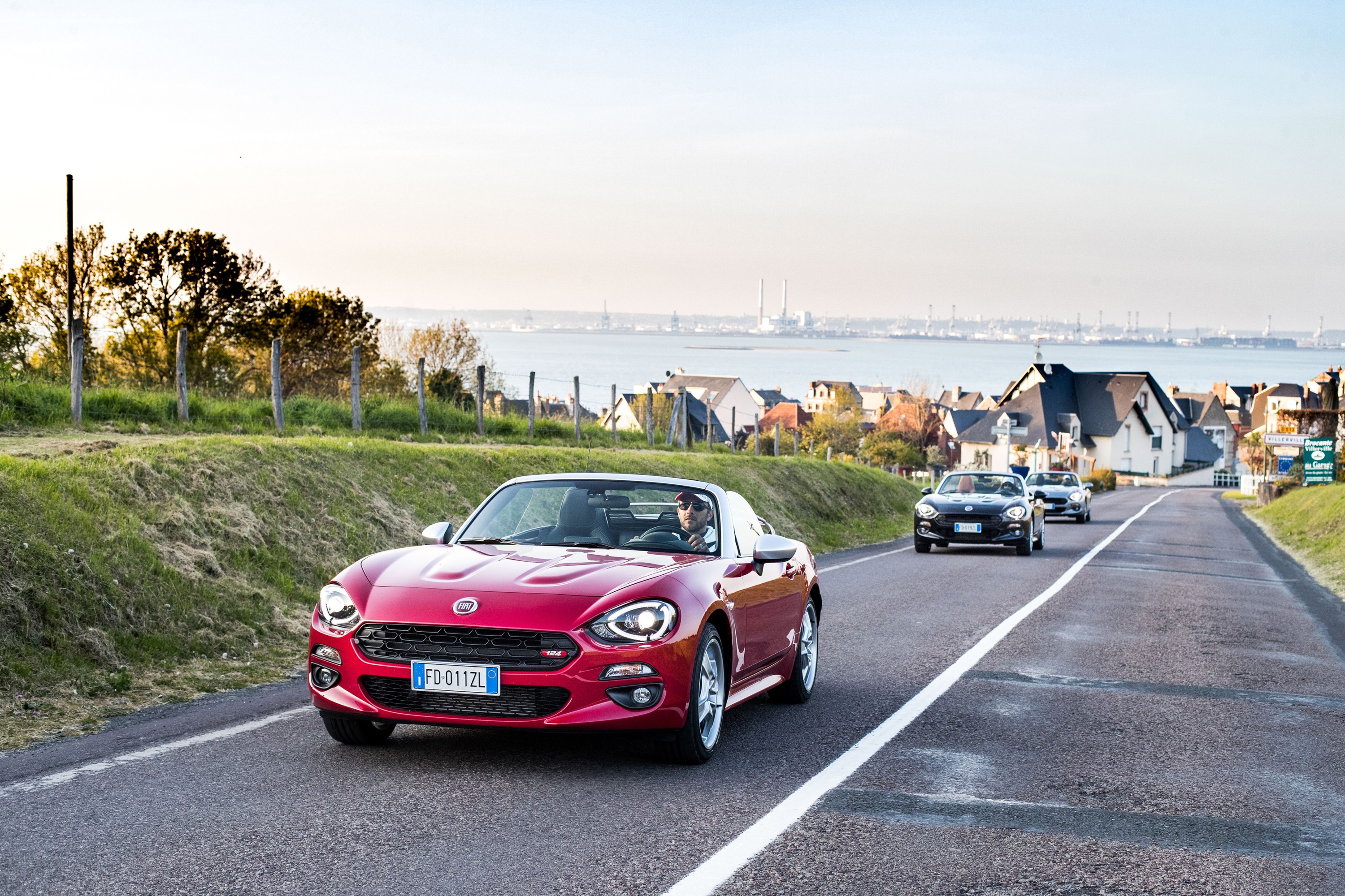 Red Fiat 124 Spider Cabriolet driving on a coastal road HD Wallpaper