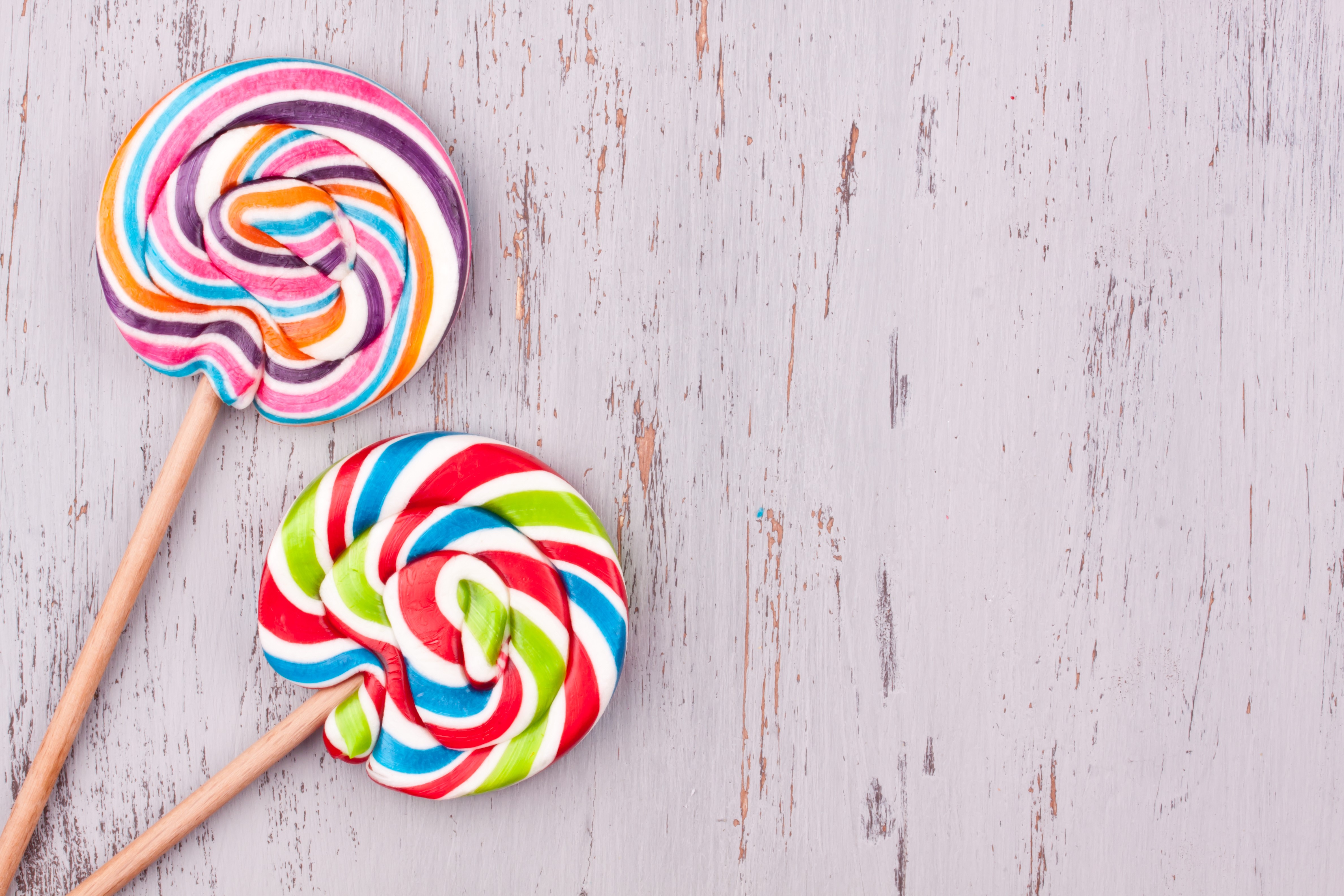 Two colorful swirl lollipops on a wooden surface HD Wallpaper