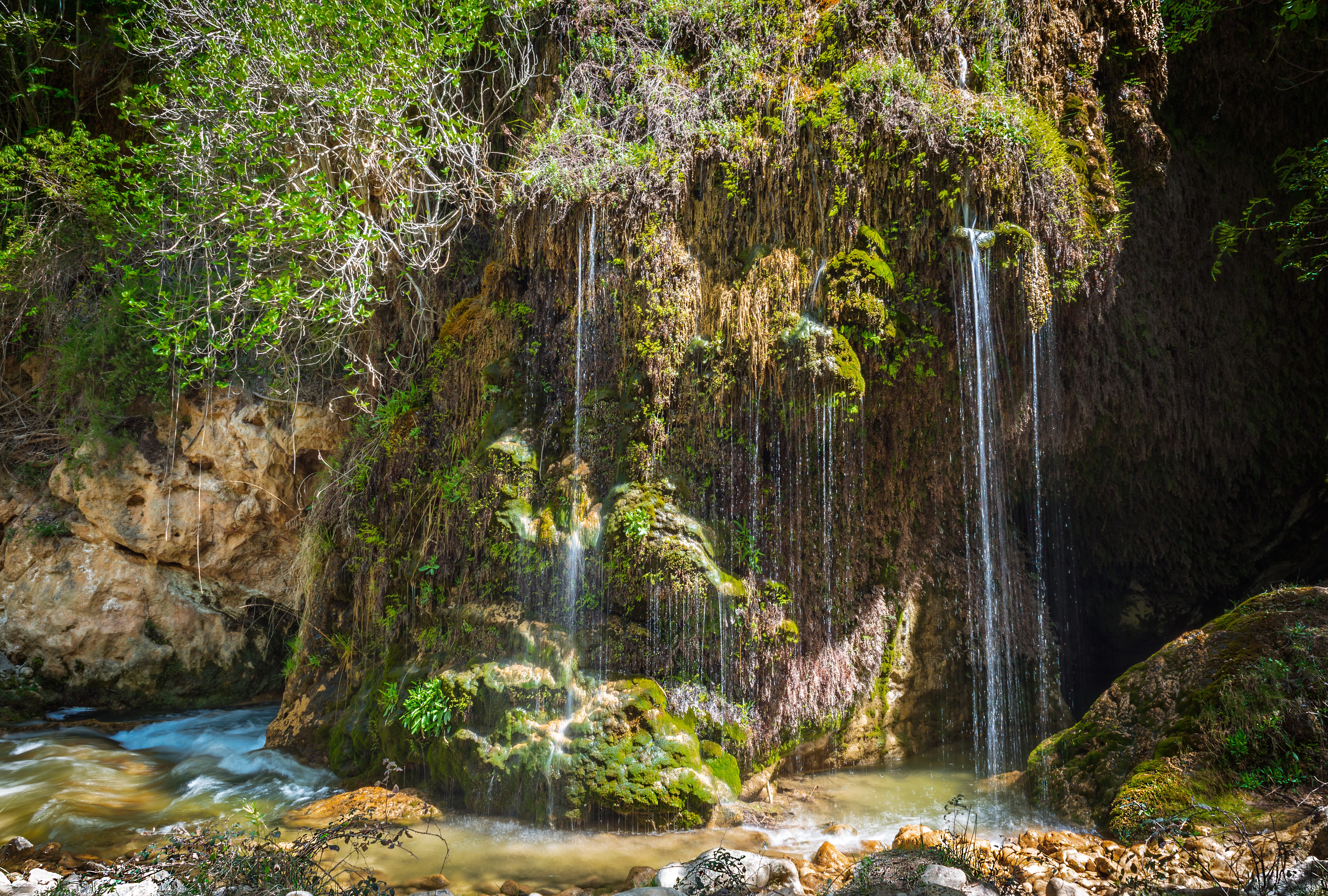 Waterfalls cascading over a moss-covered crag HD Wallpaper