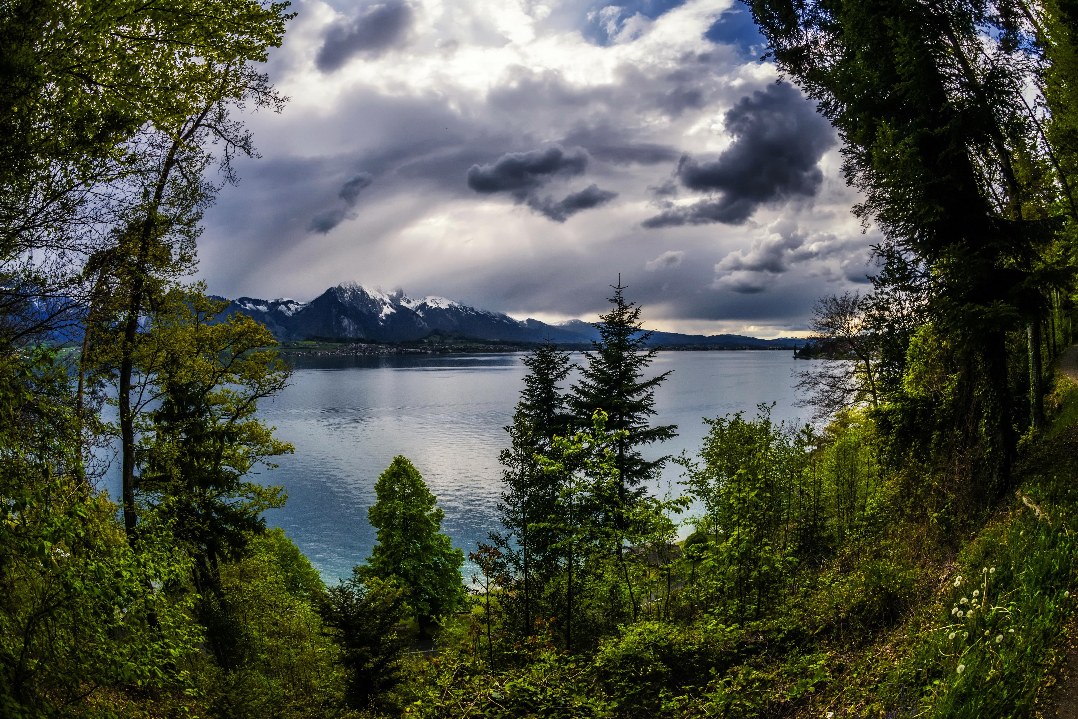 Lake Thun with snow-capped mountains and stormy clouds in Switzerland HD Wallpaper