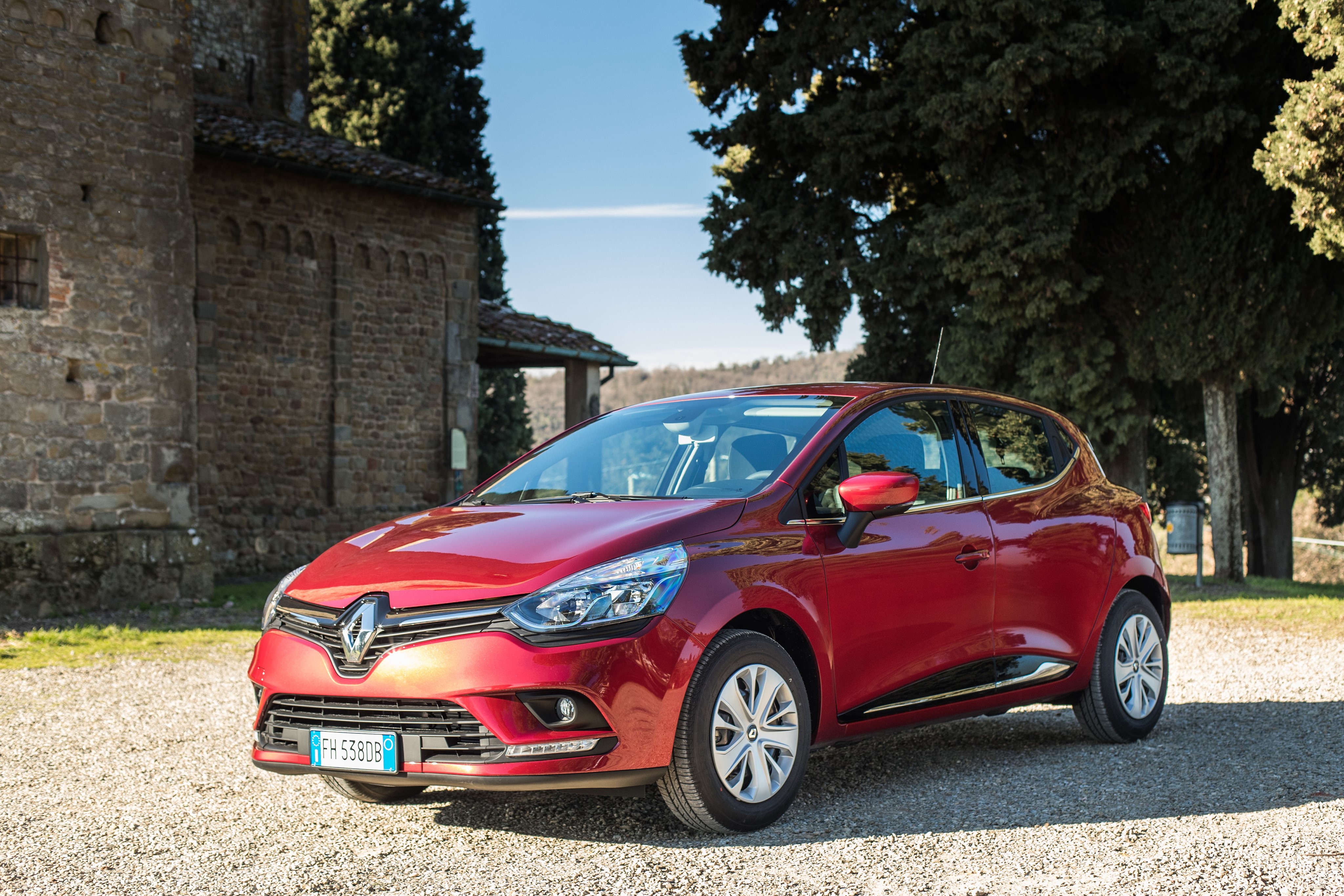 Red Renault Clio parked in front of a stone building HD Wallpaper