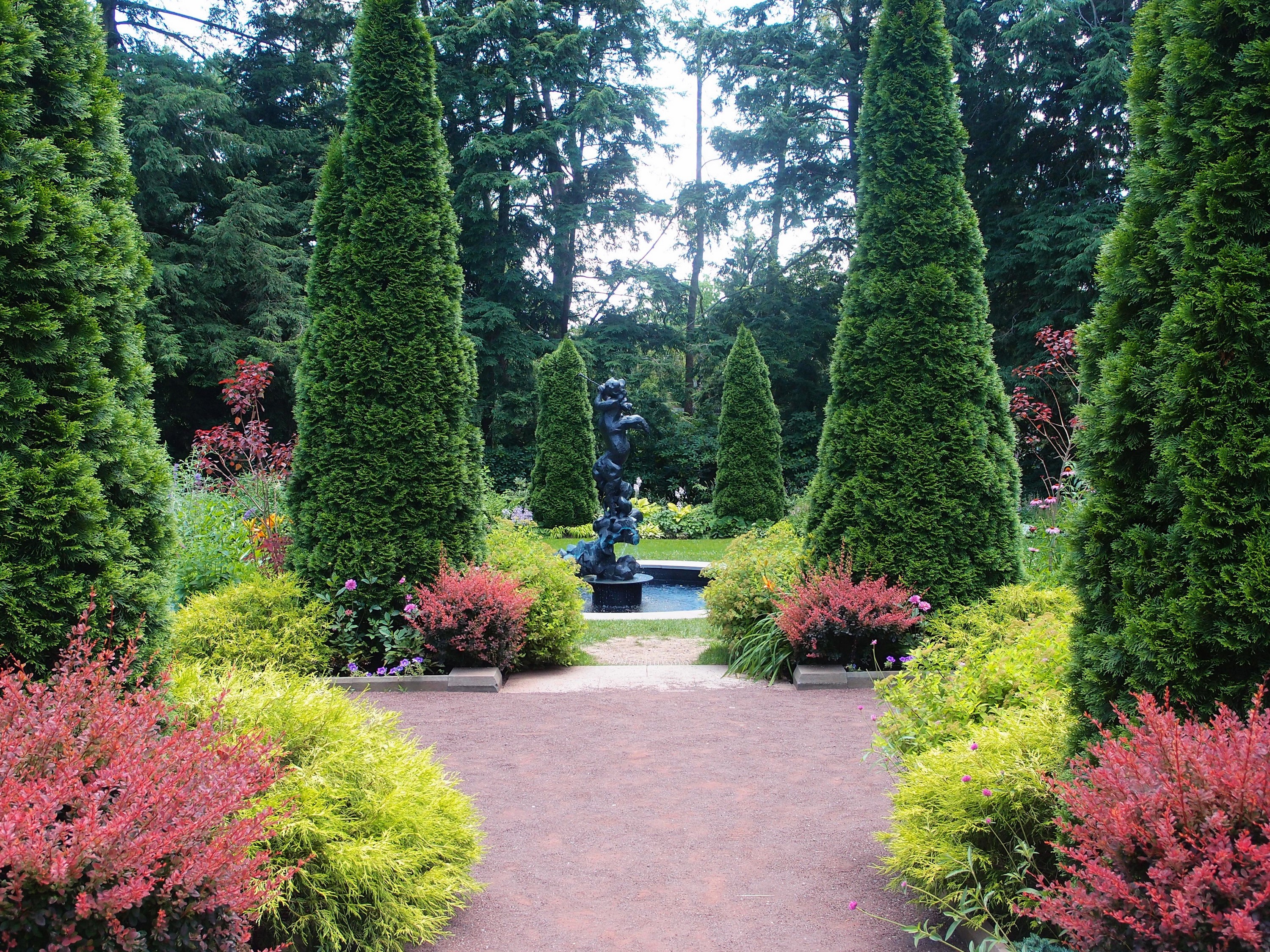Garden with sculptures and manicured shrubs HD Wallpaper