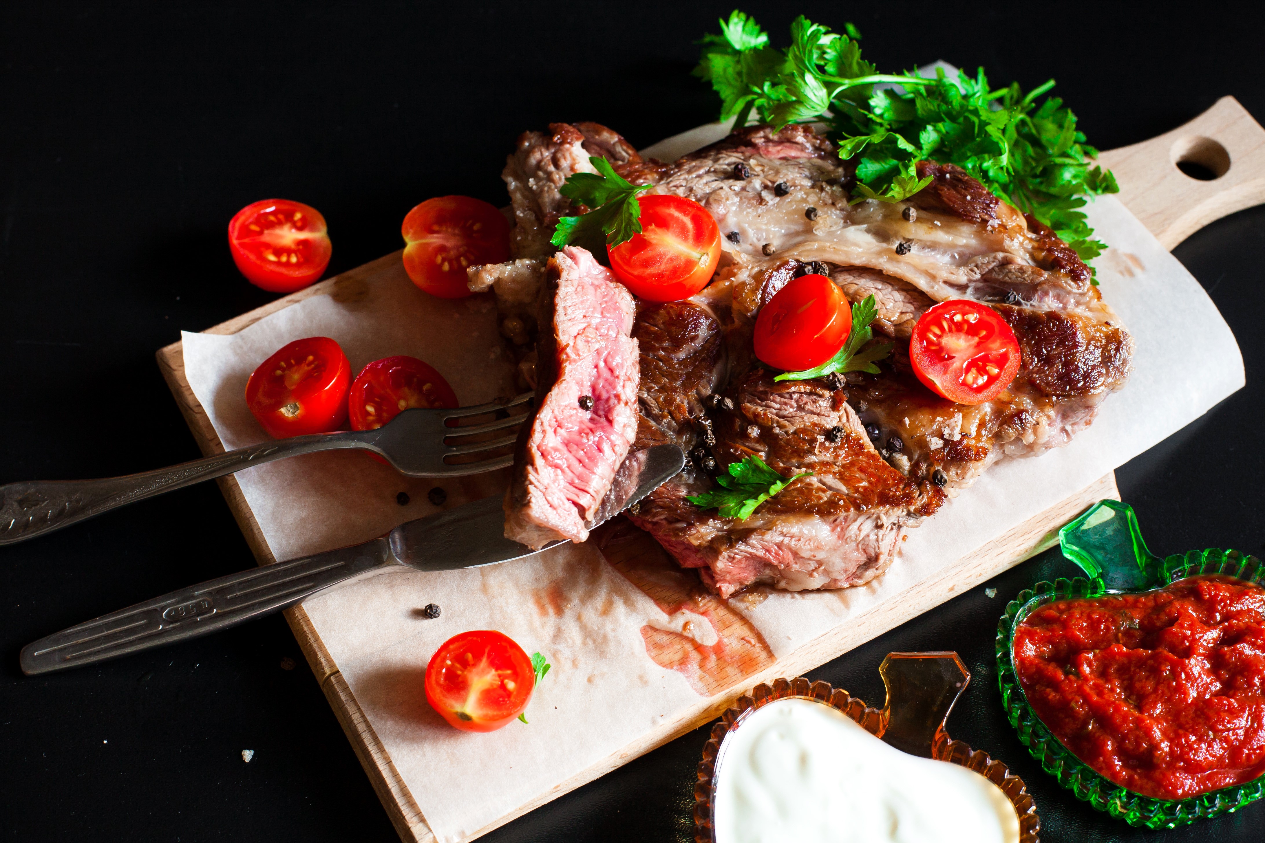Steak with tomatoes and sauces on a cutting board HD Wallpaper