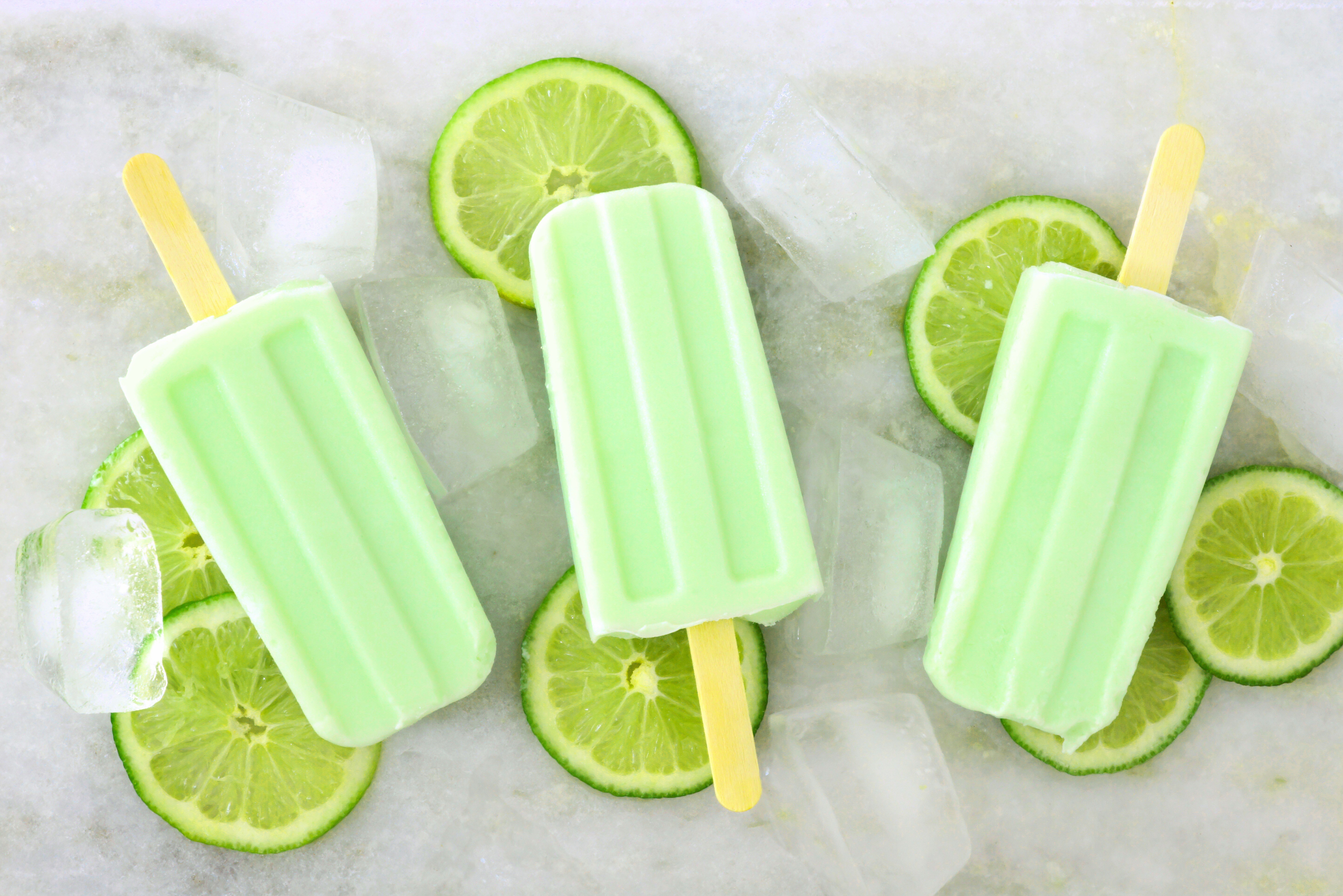 Three lime popsicles with ice and lime slices HD Wallpaper