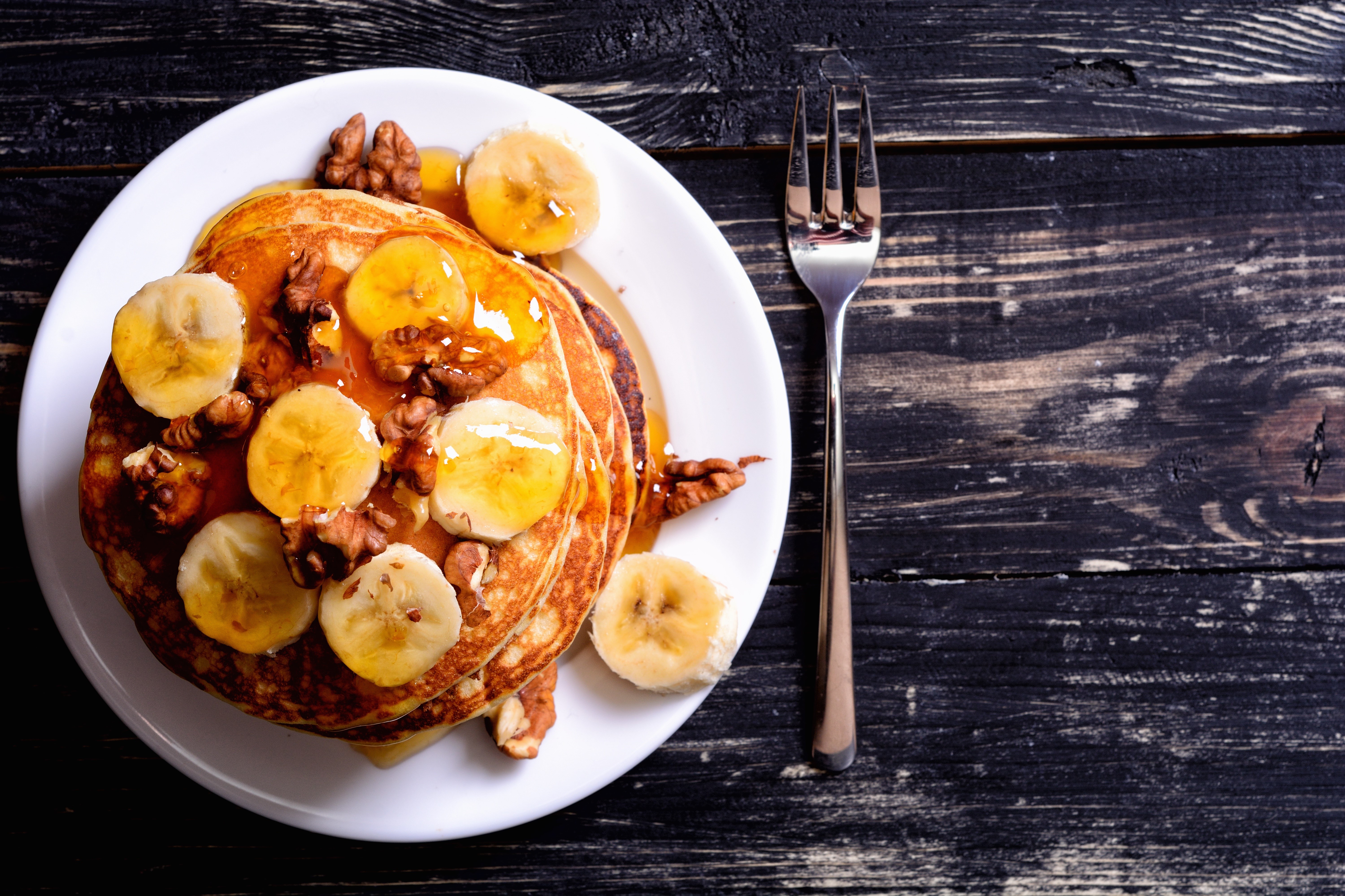Pancakes with bananas and walnuts on a plate with a fork HD Wallpaper