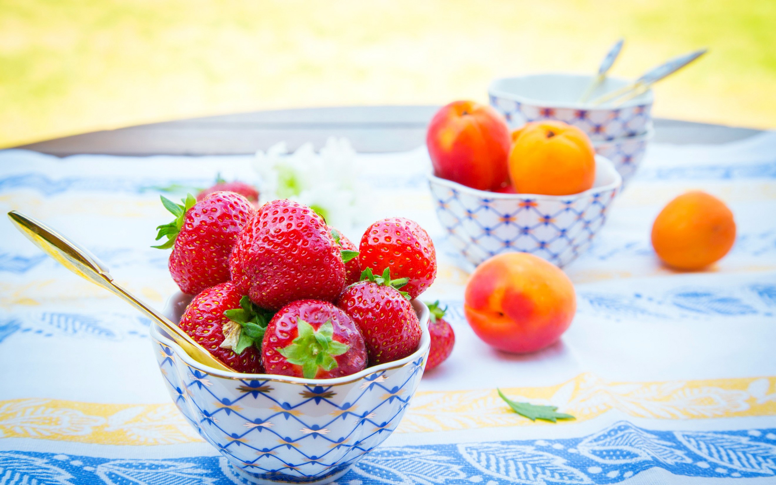 Strawberries and peaches in bowls on a table HD Wallpaper