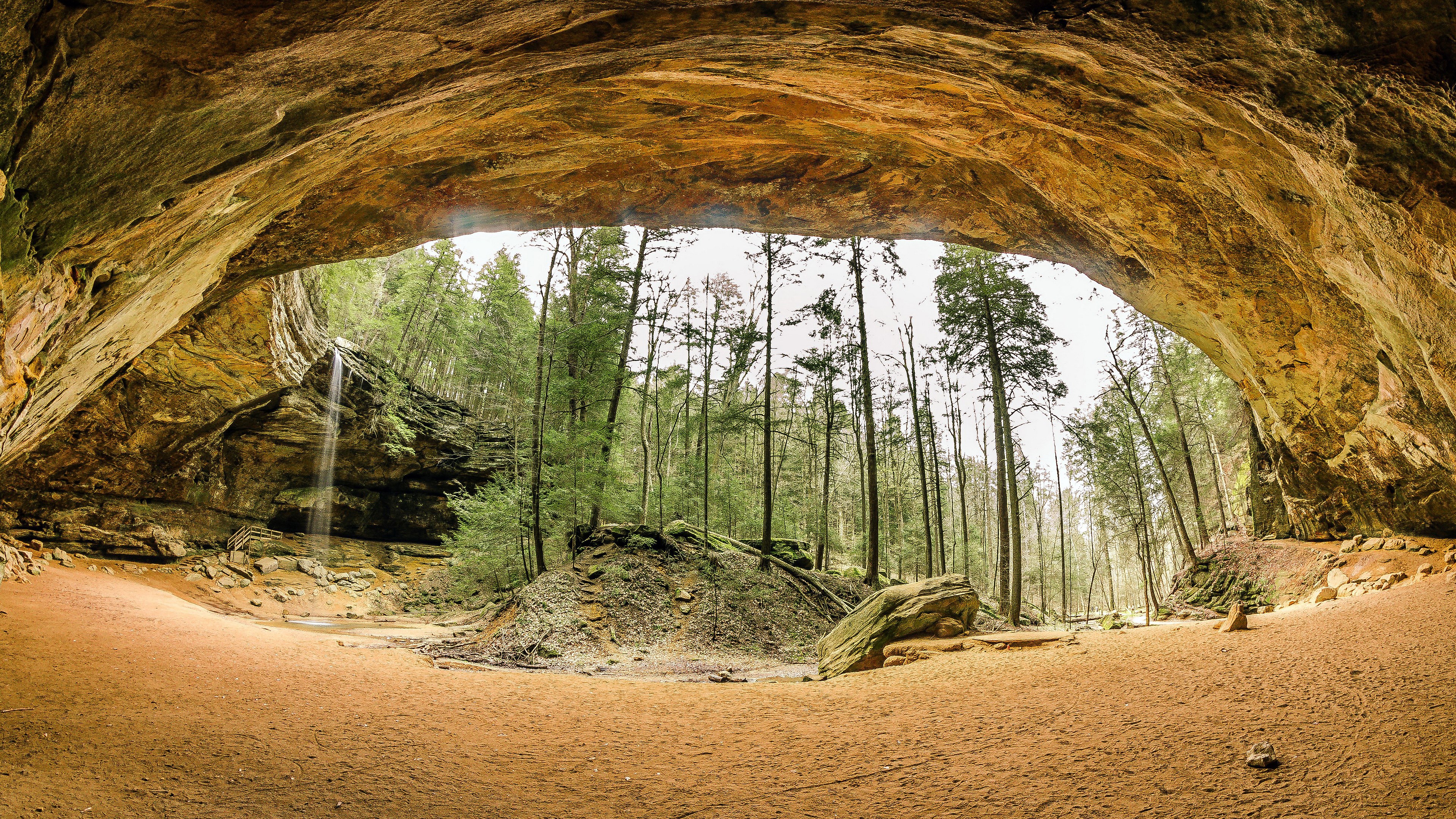 Cave opening with waterfall and forest HD Wallpaper