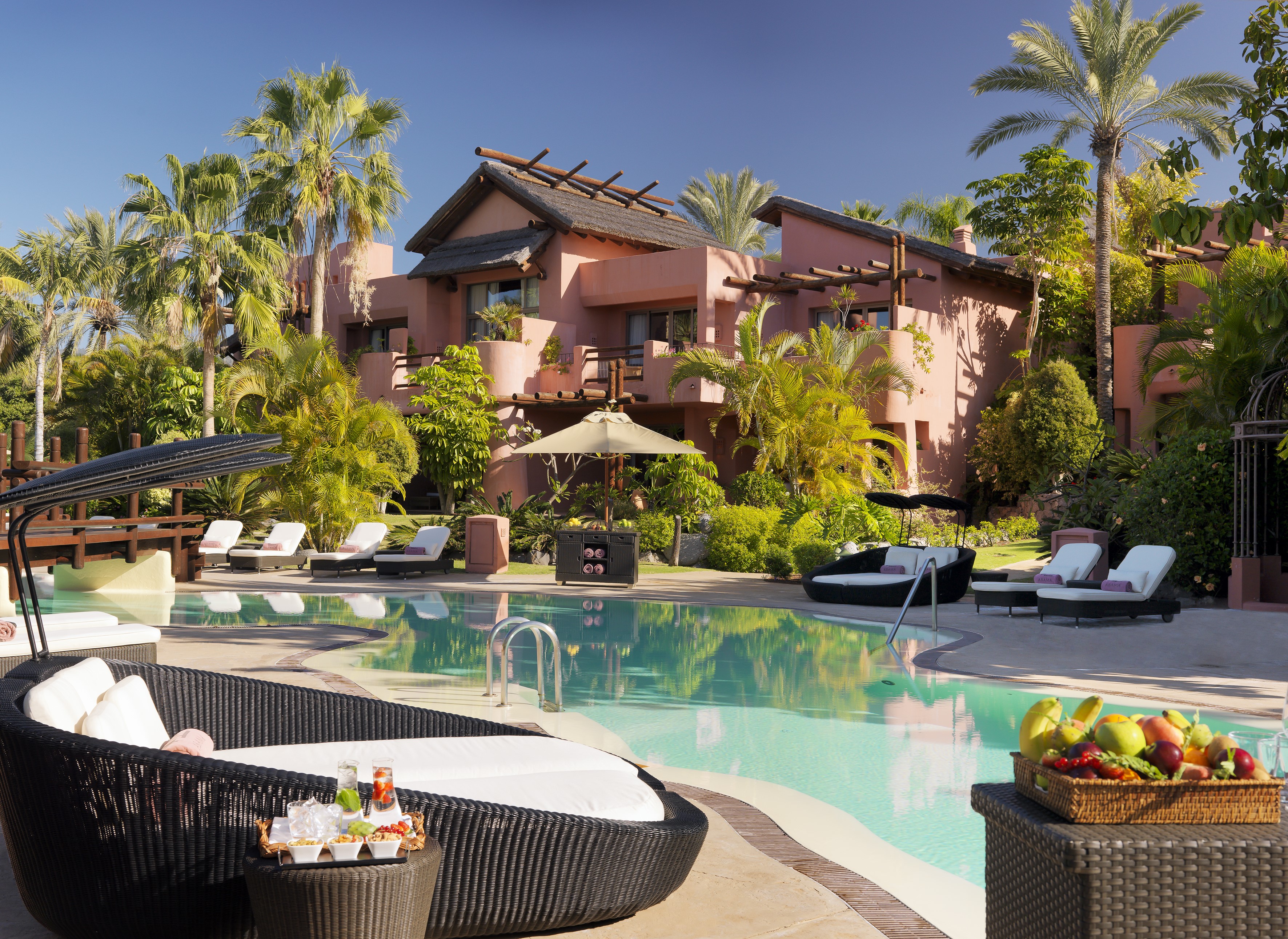 Resort with pool, sunloungers, and palm trees in Tenerife, Spain HD Wallpaper