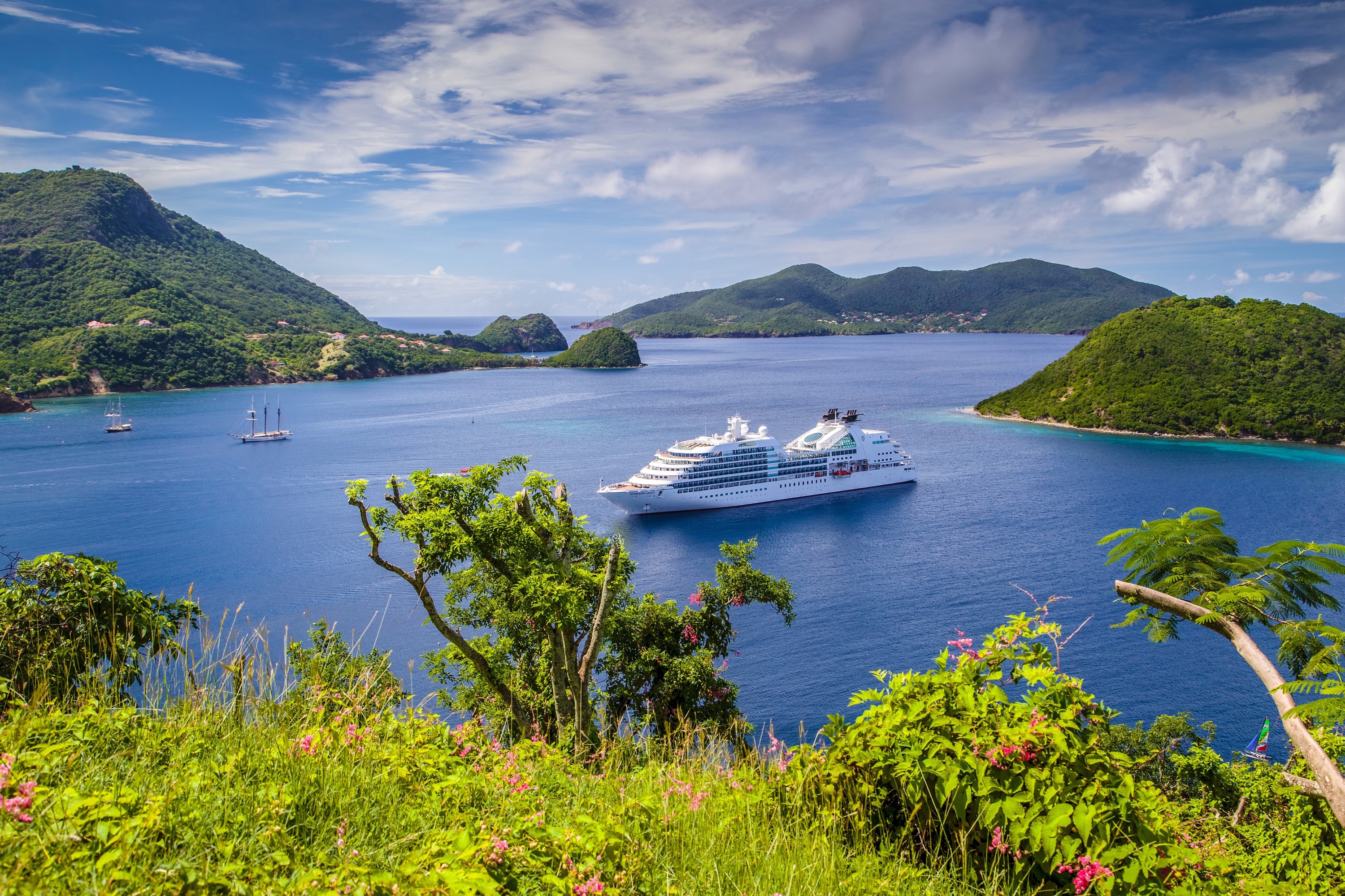 Cruise liner in a bay with green hills and sailboats HD Wallpaper
