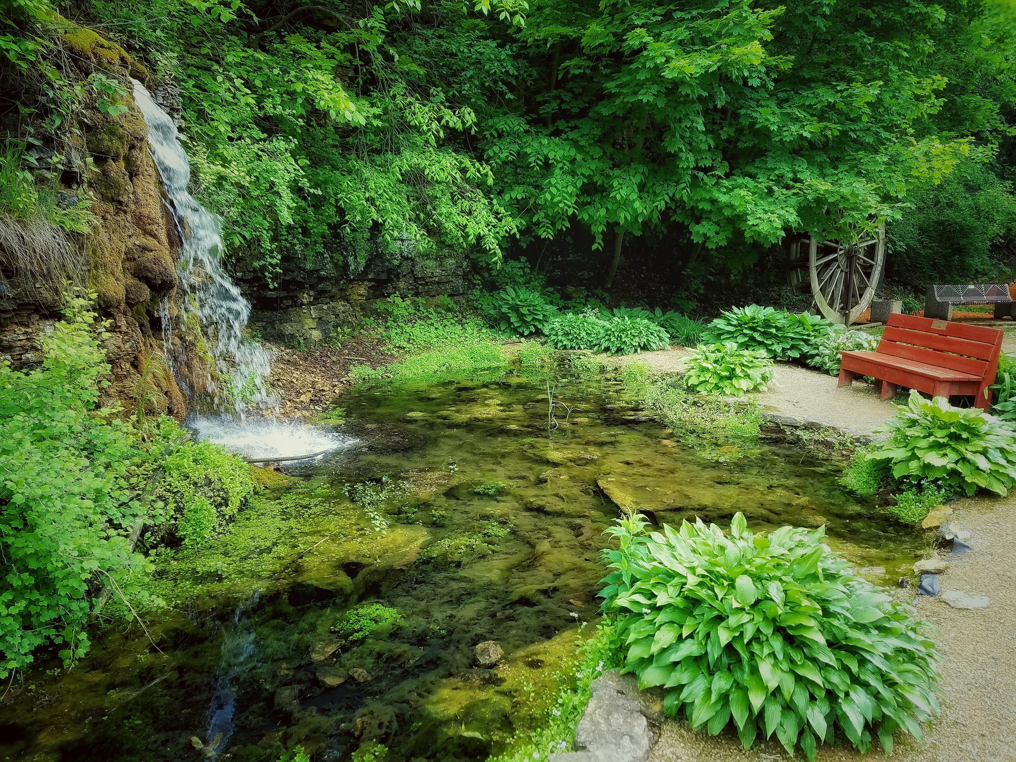 Waterfall and pond in a park with a bench HD Wallpaper
