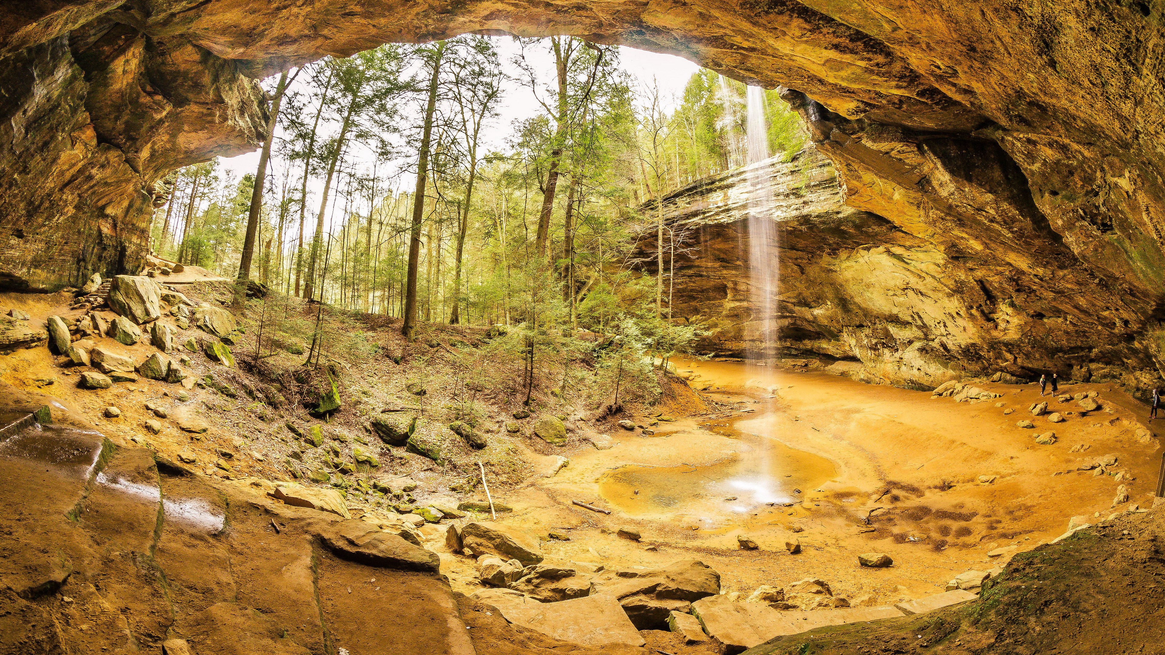 Waterfall cascading into a cave with trees and rocks HD Wallpaper