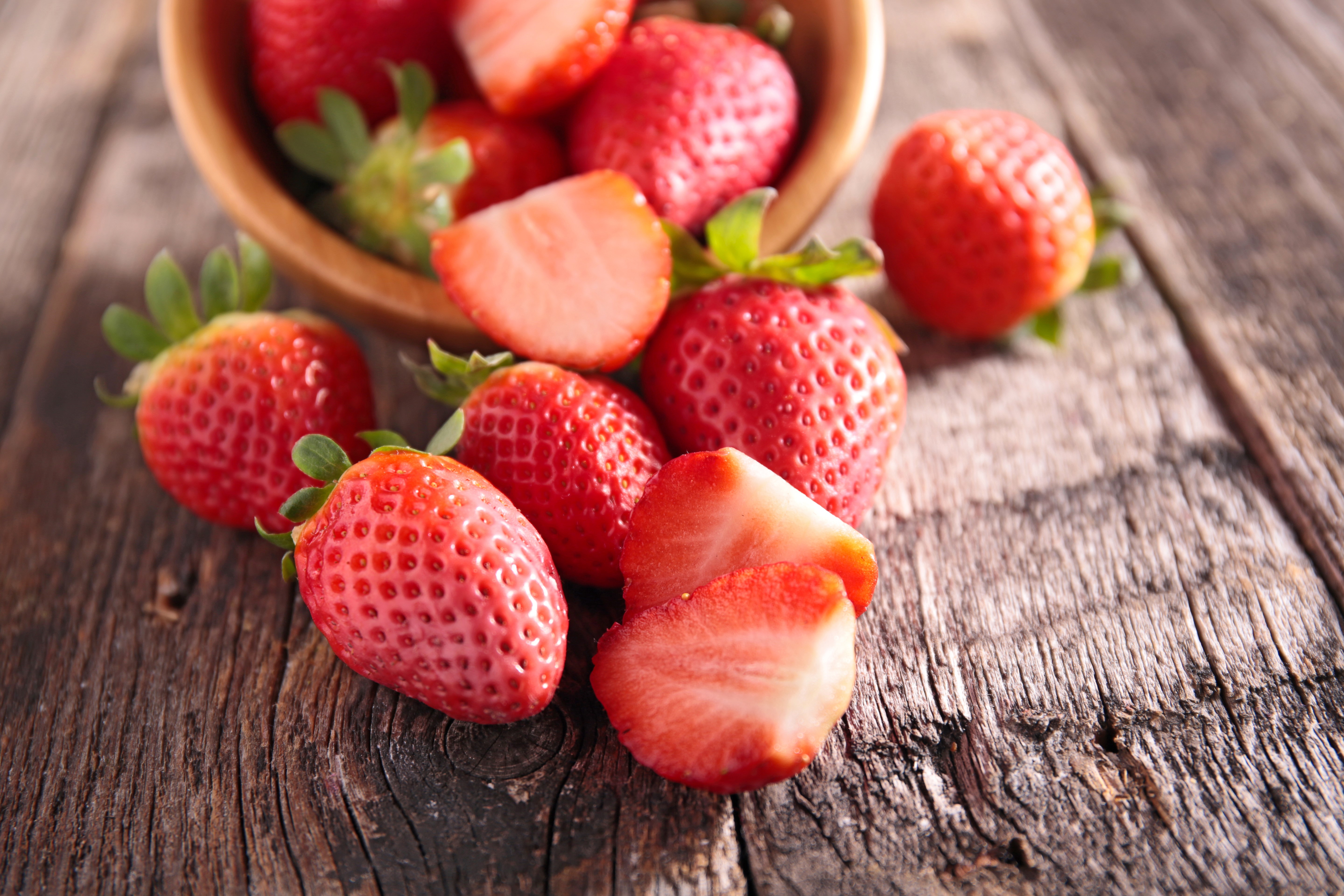 Strawberries in a bowl on a wooden table HD Wallpaper