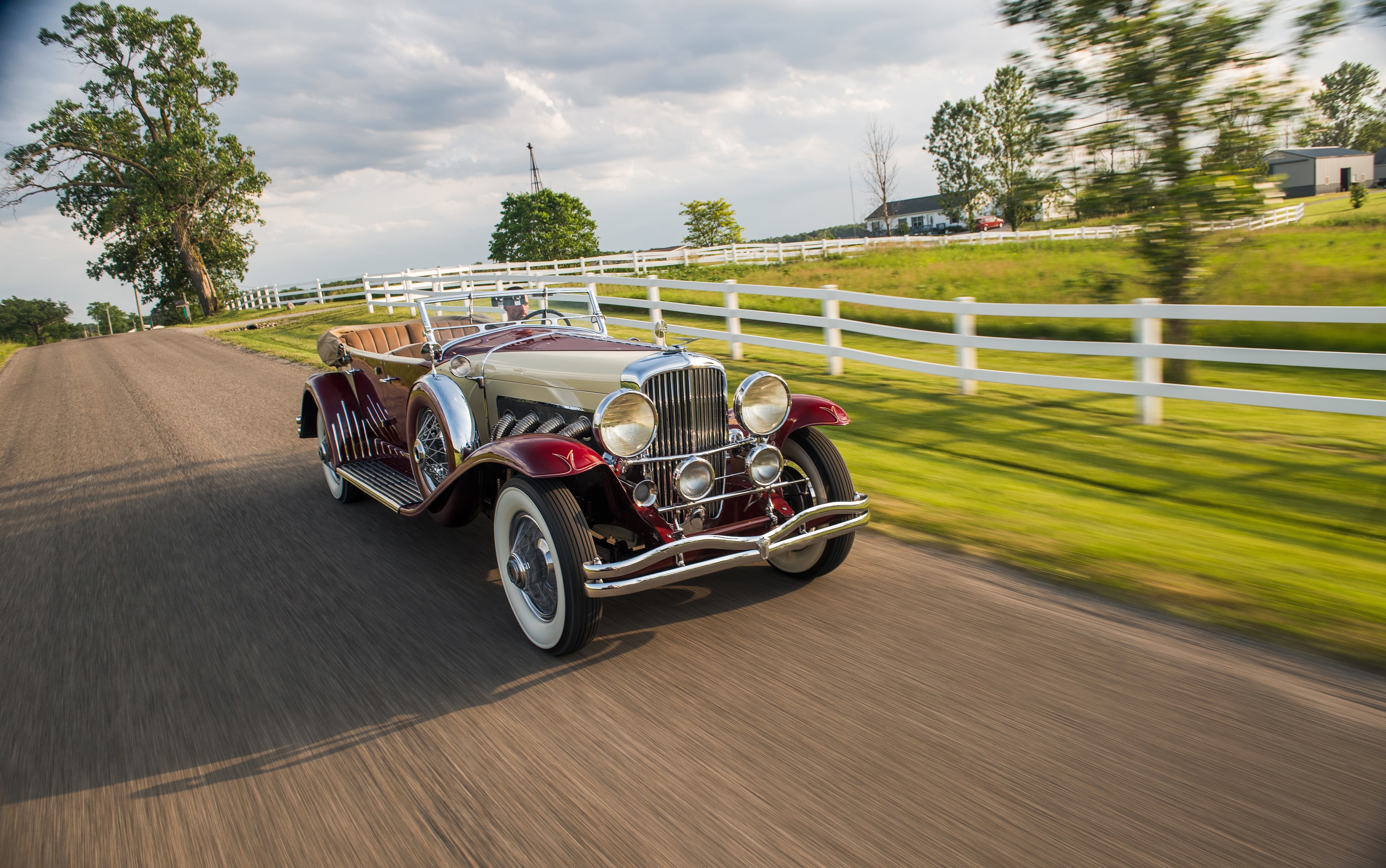 1933 Duesenberg SJ Phaeton driving on a country road HD Wallpaper