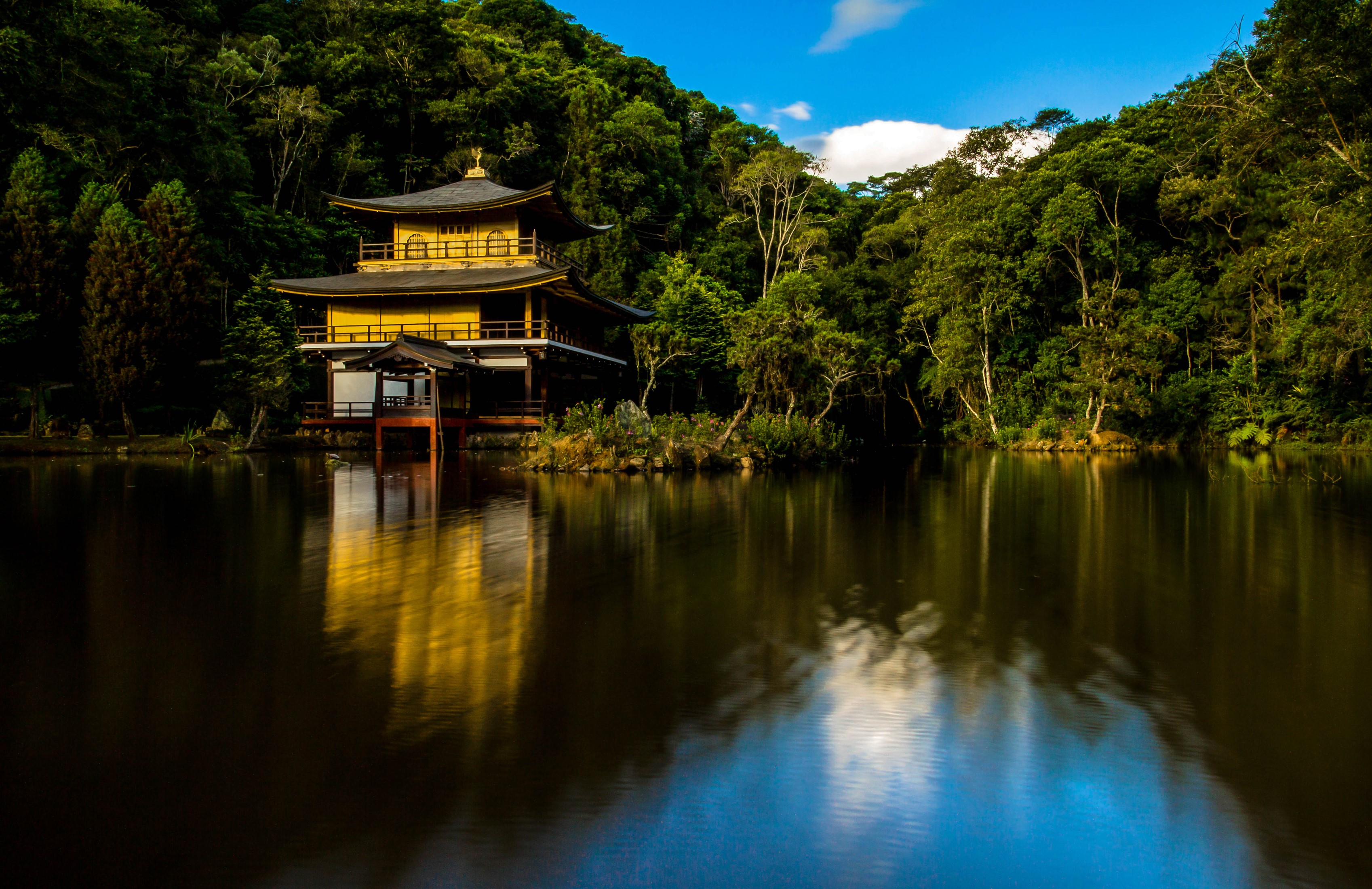 Golden Pavilion Temple reflected in a lake surrounded by trees HD Wallpaper