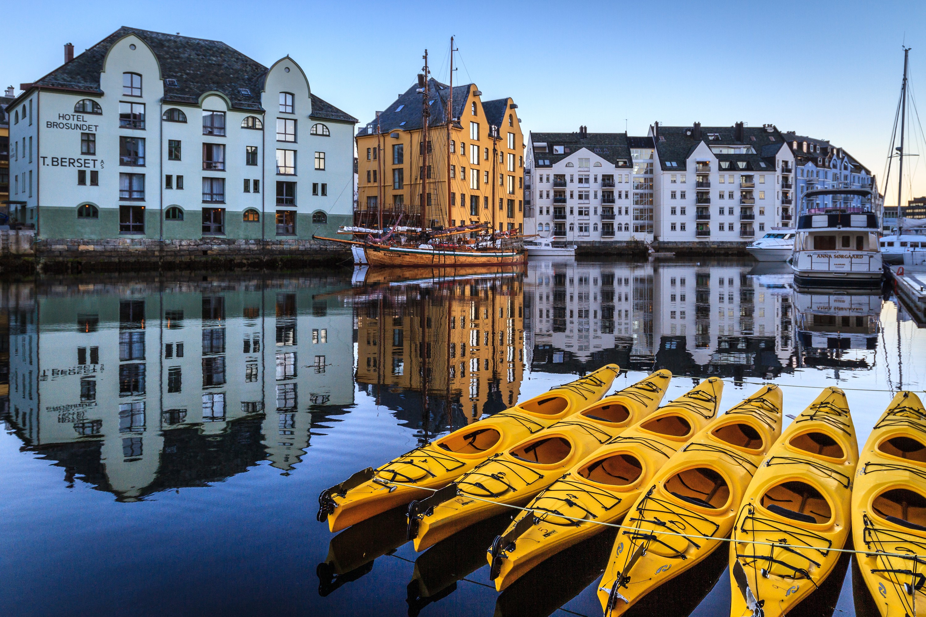 Kayaks and buildings reflected in water in Alesund, Norway HD Wallpaper