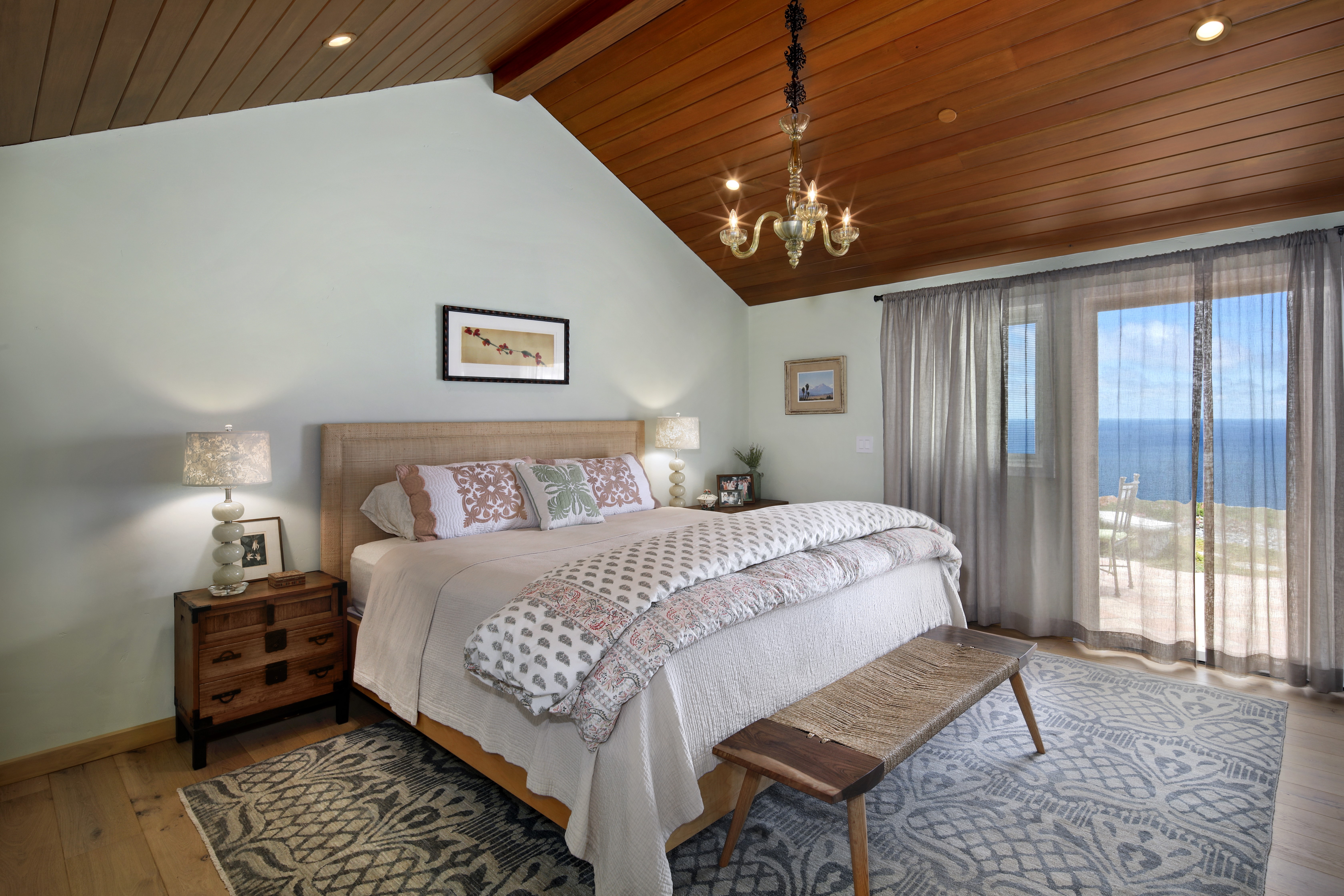 Bedroom with ocean view, chandelier, and lamps HD Wallpaper