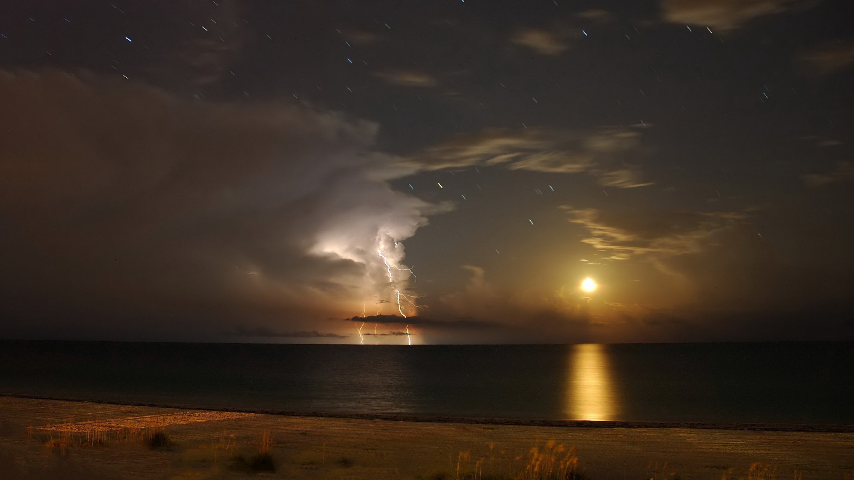 Lightning strikes over the ocean at night with moon HD Wallpaper