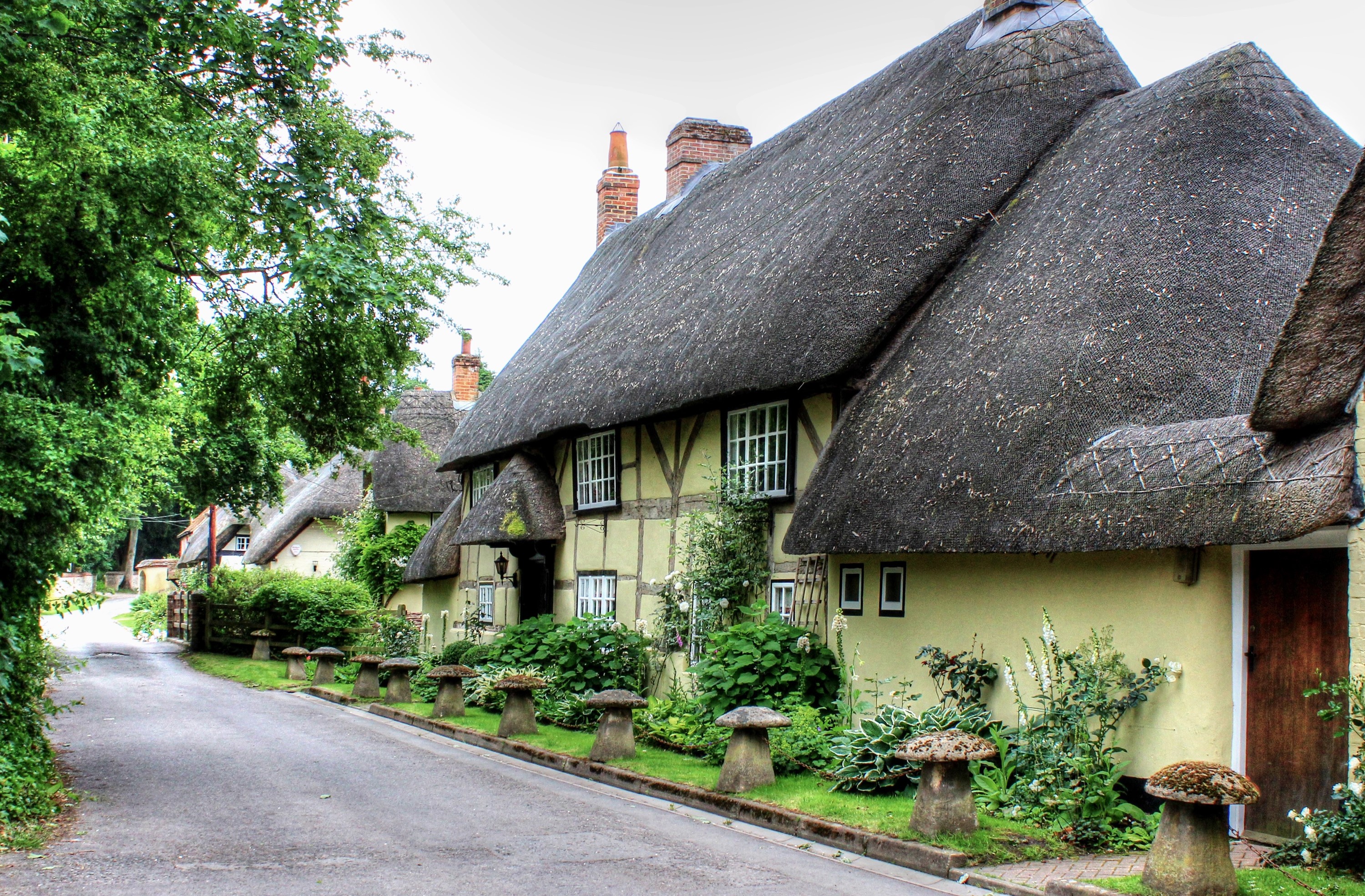 Thatched roof cottages on a street in Wherwell, England HD Wallpaper