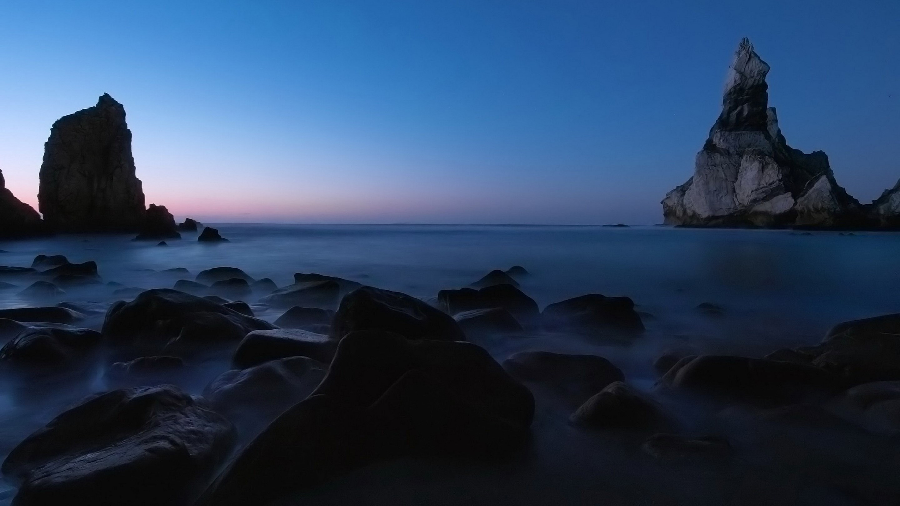 Rocky coastline at dusk with ocean waves HD Wallpaper