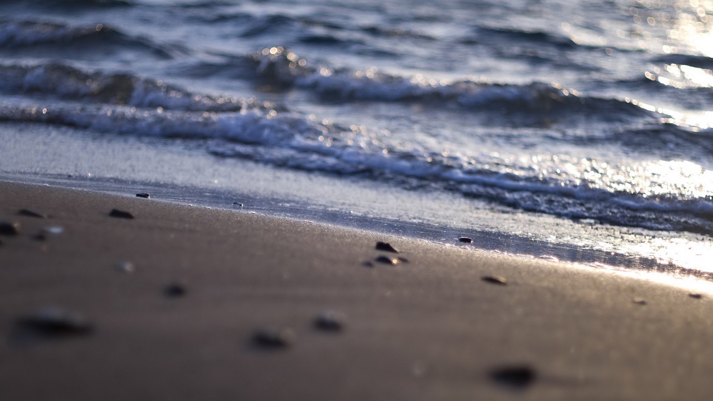 Waves washing over a sandy beach with pebbles HD Wallpaper