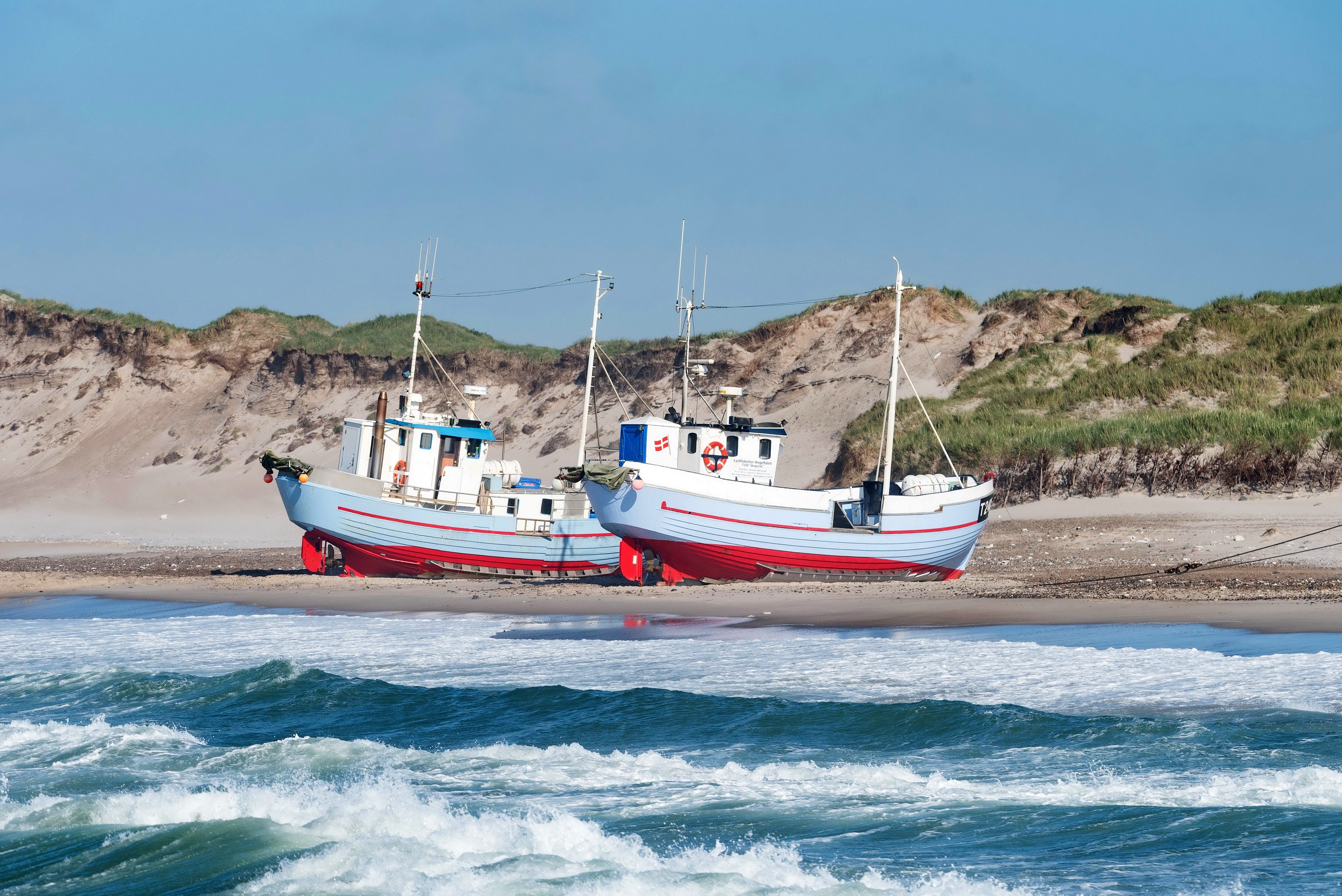 Two fishing boats on a sandy beach with dunes and waves HD Wallpaper