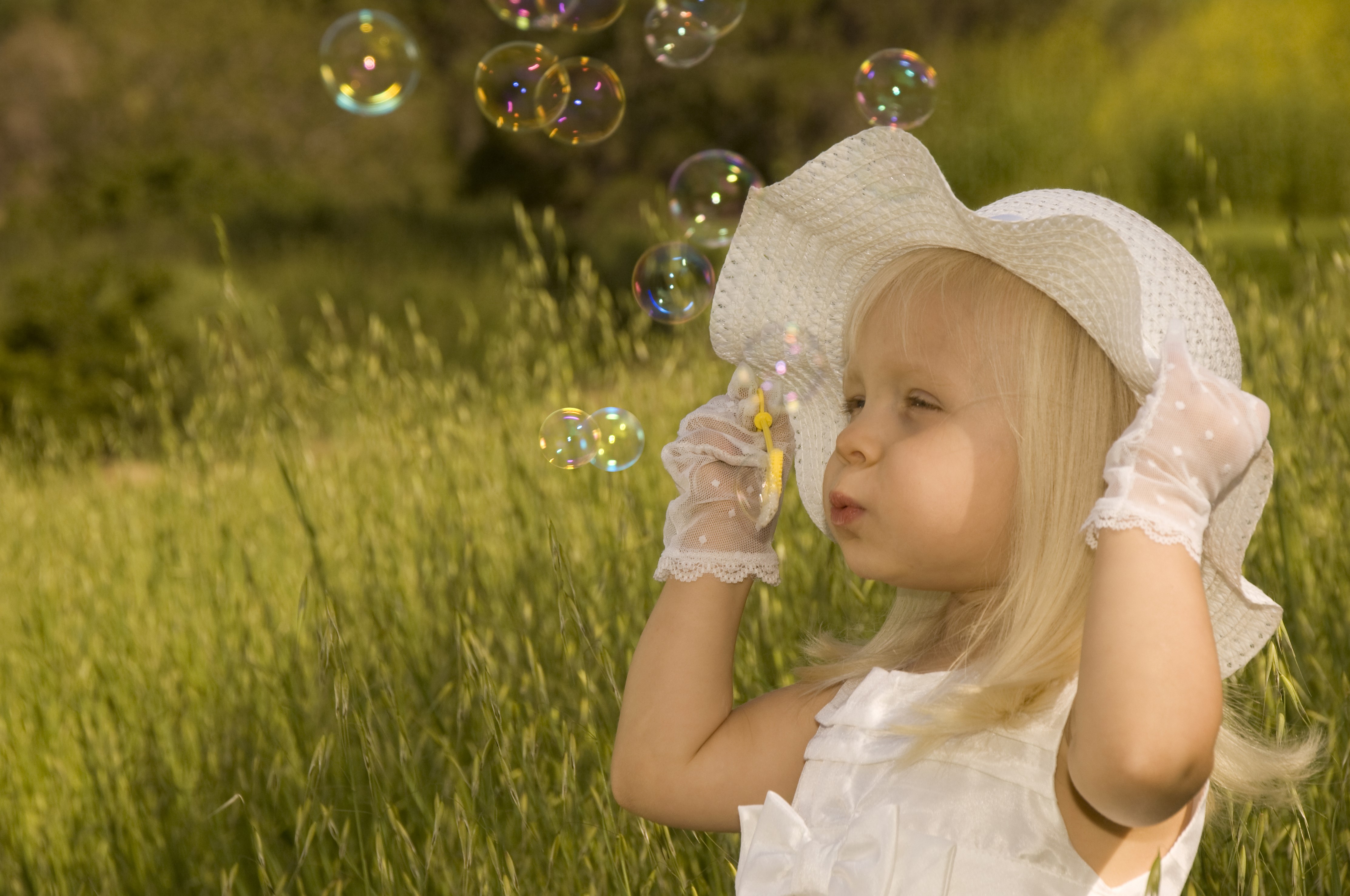 Little girl in hat blowing soap bubbles HD Wallpaper
