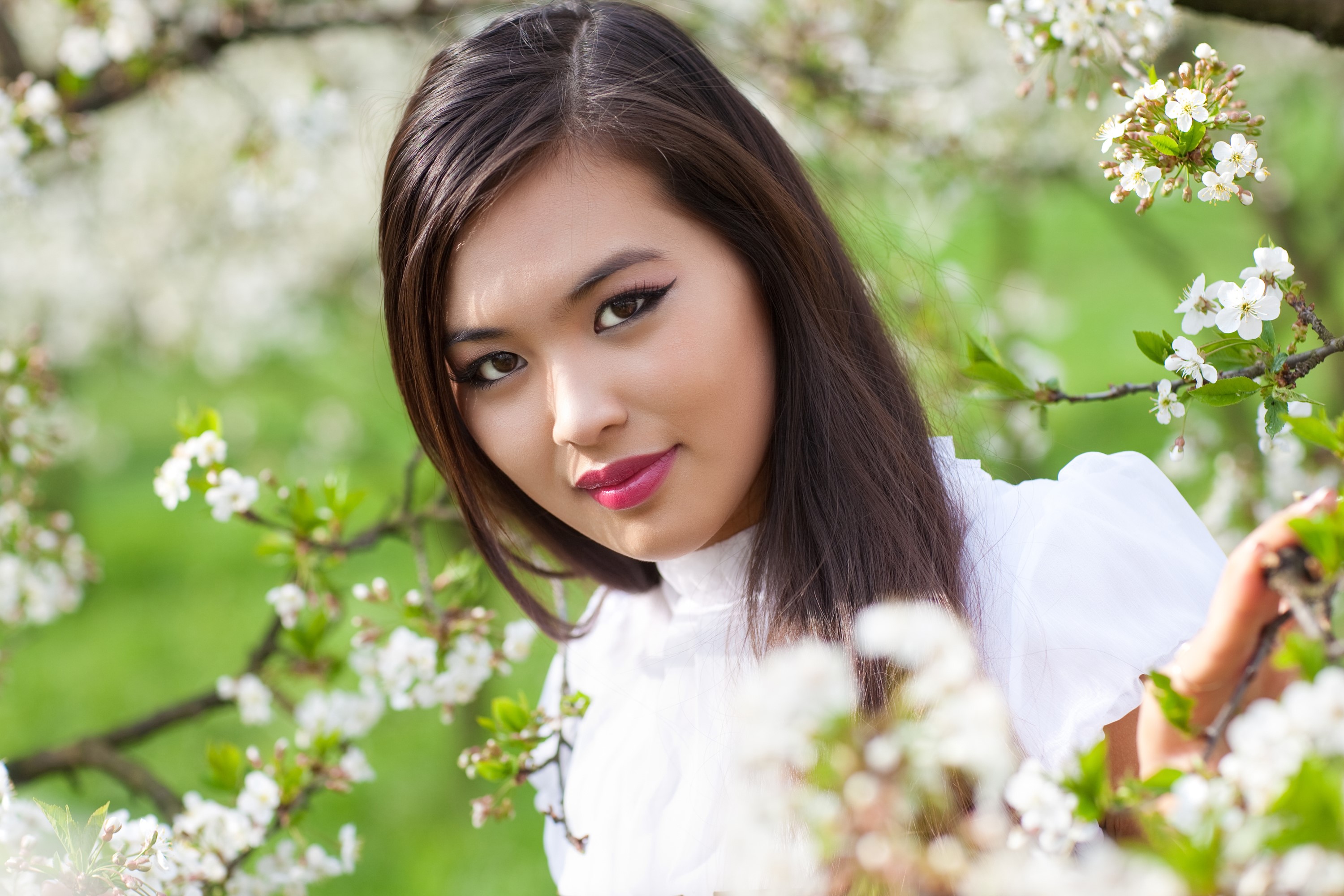 Beautiful Asian woman with brown hair among blooming branches HD Wallpaper