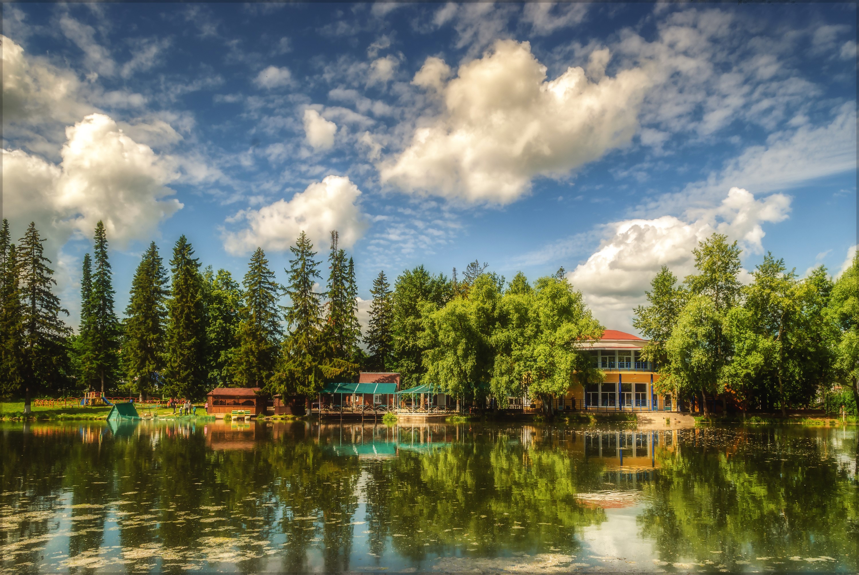 Building by the river with trees and clouds HD Wallpaper