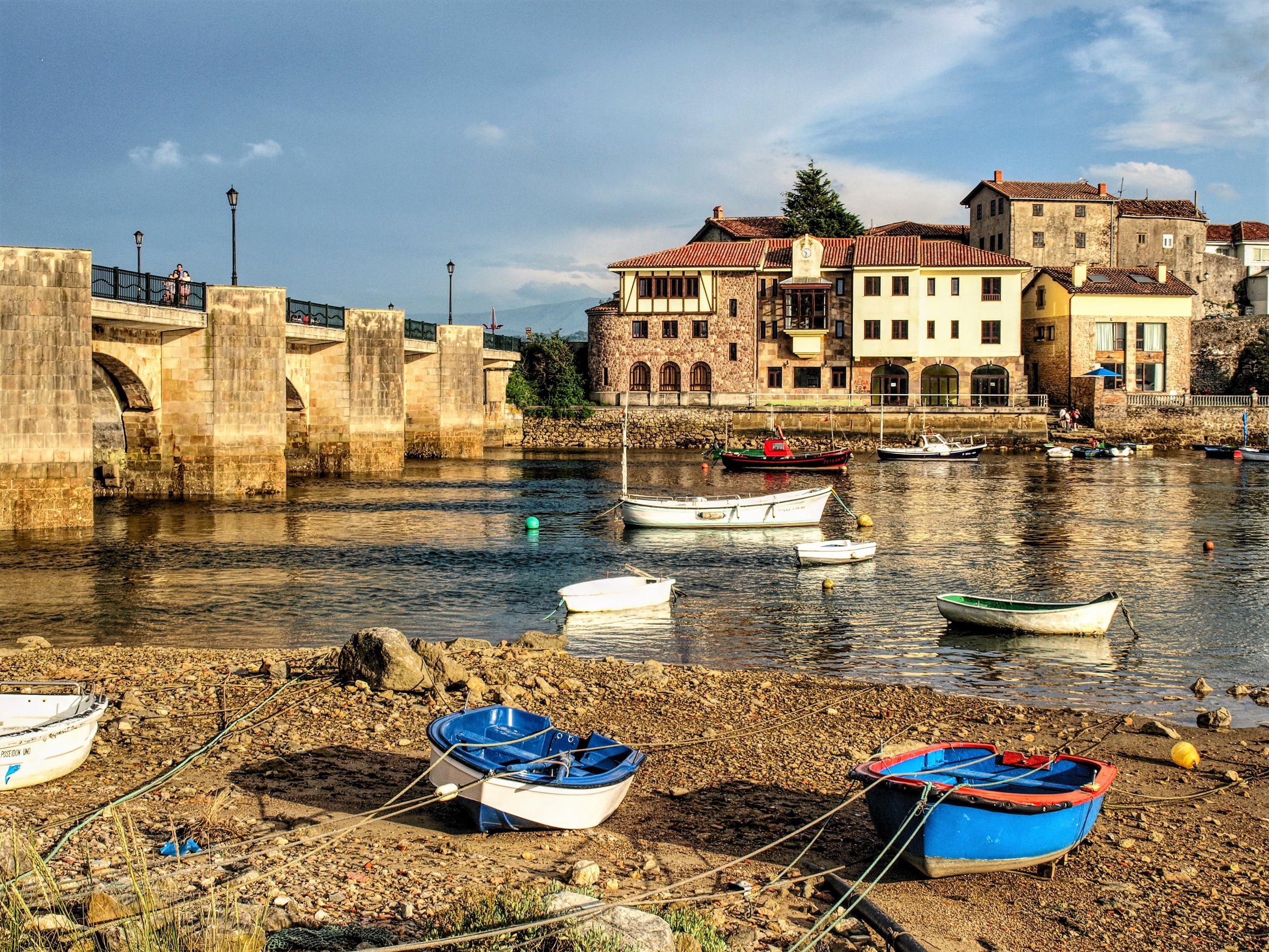 Boats on the river with a stone bridge and buildings in San Vicente de la Barquera, Spain HD Wallpaper