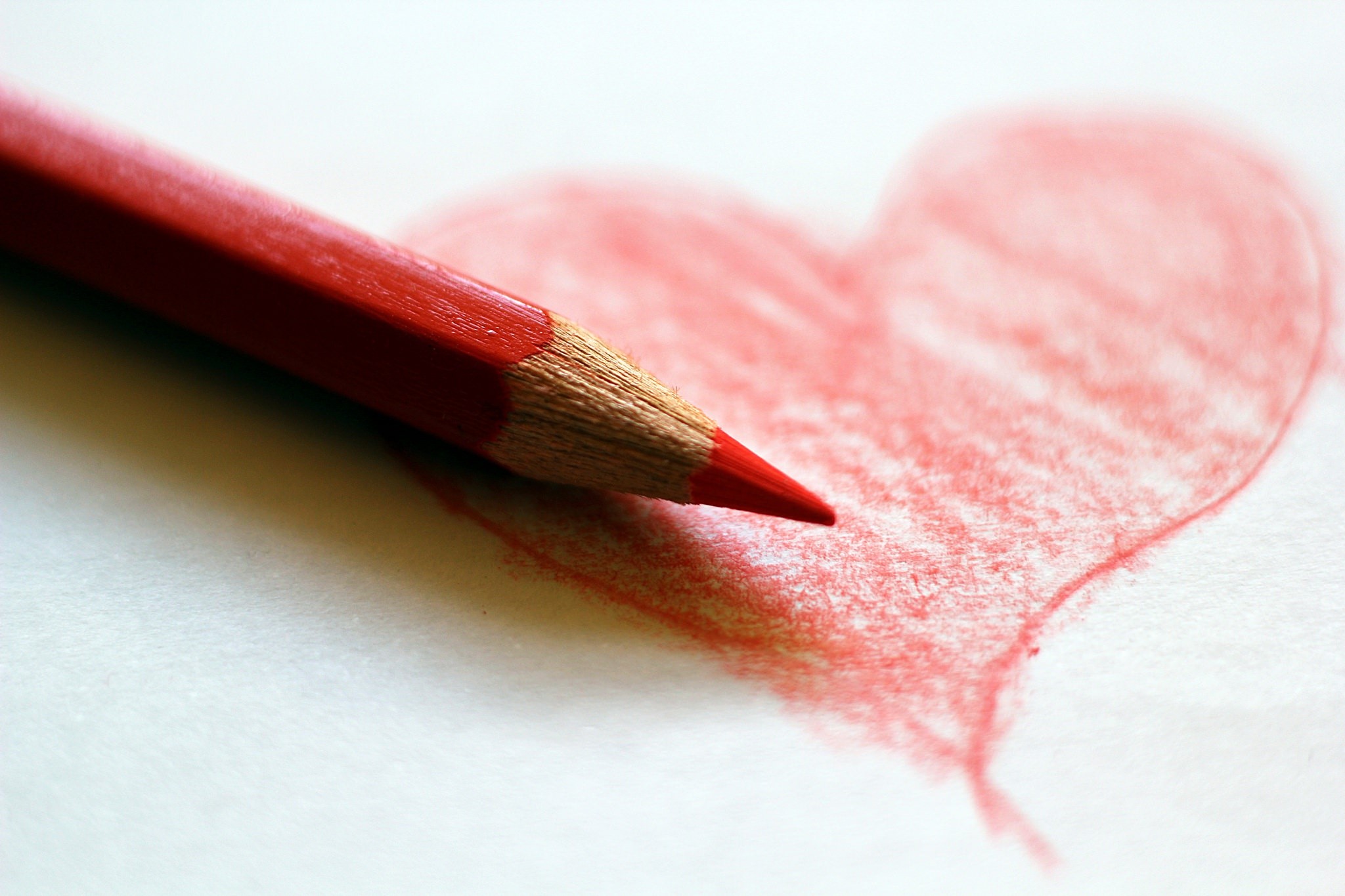 Red pencil drawing a heart on white paper HD Wallpaper