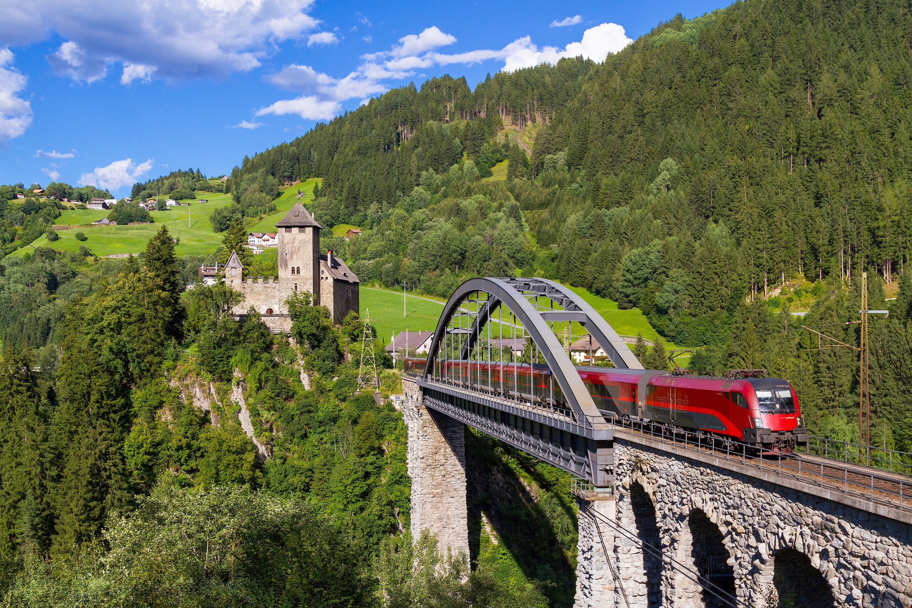Red train crossing a stone bridge in Austria HD Wallpaper