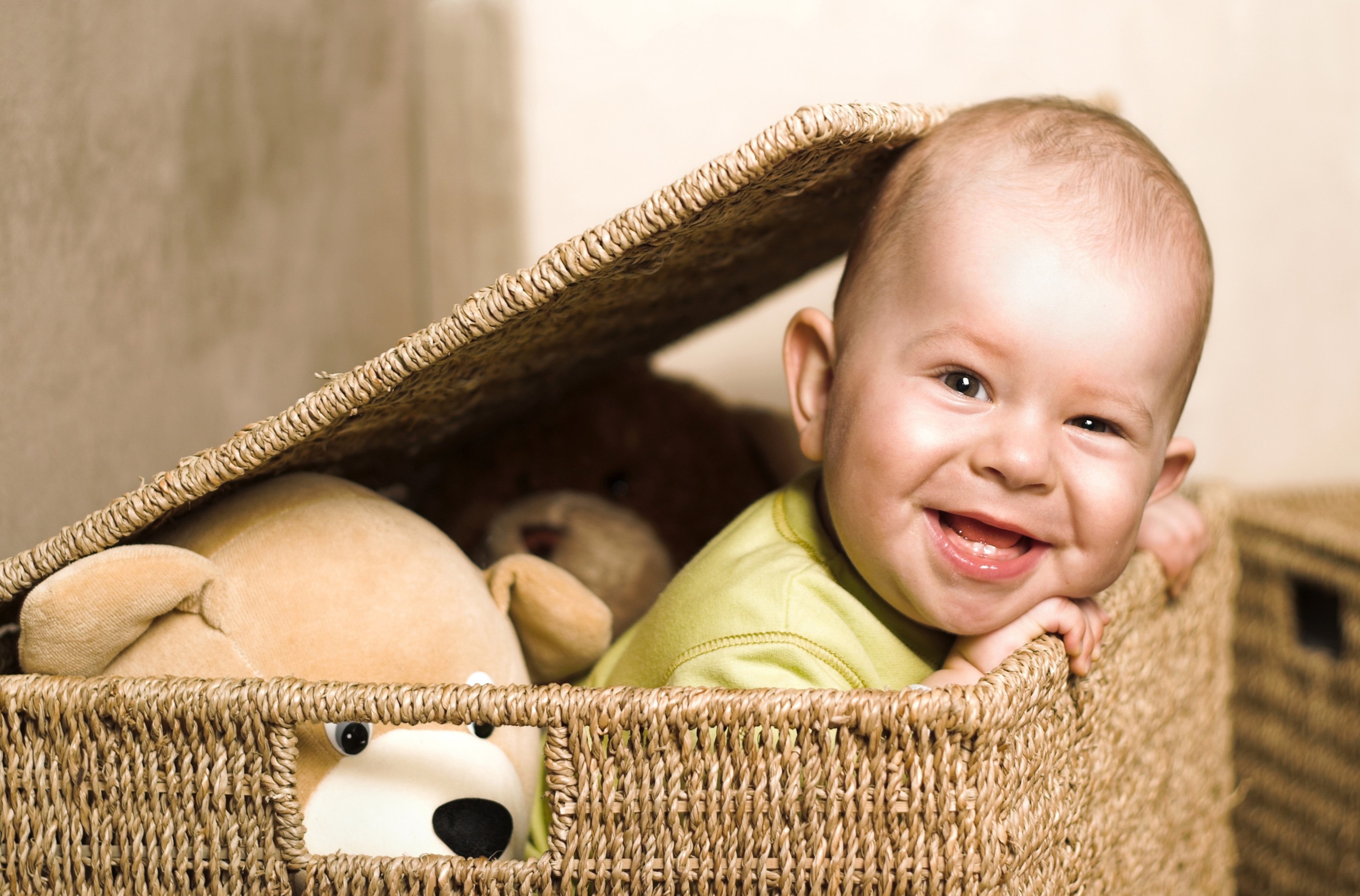 Baby smiling in a wicker basket with teddy bears HD Wallpaper