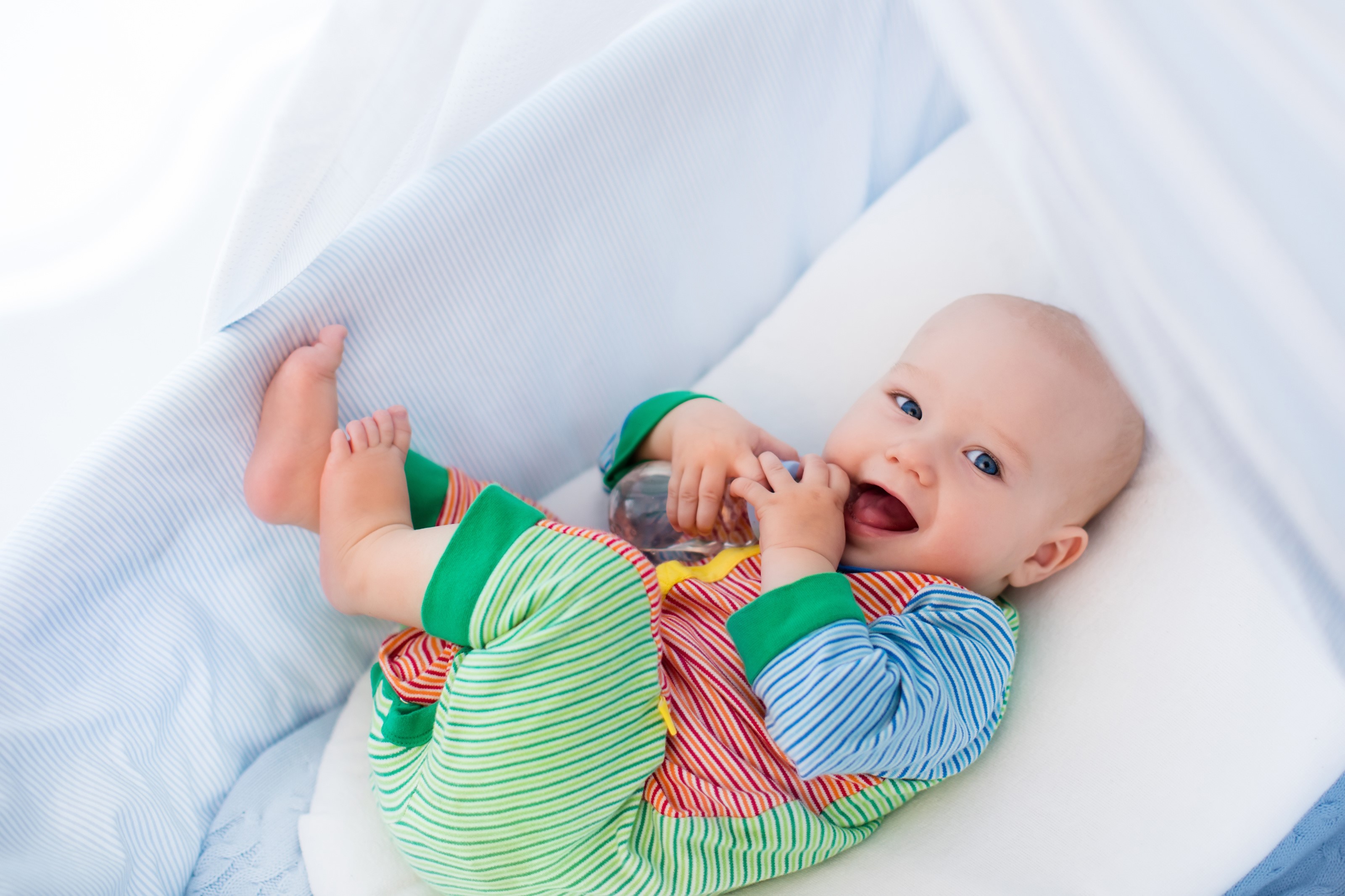 Baby lying on a white pillow and blue bedding HD Wallpaper