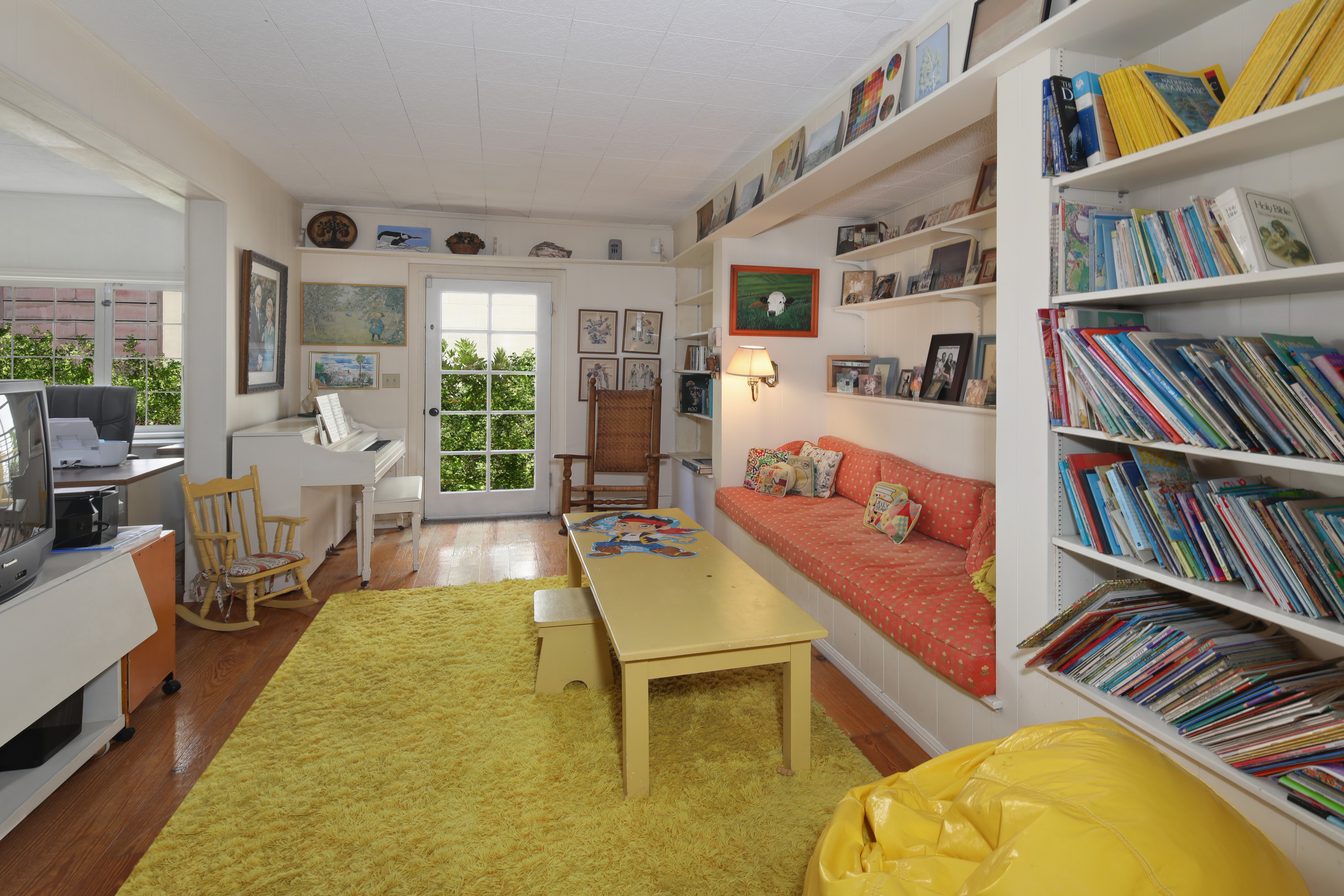 Living room with piano, sofa, and bookshelves HD Wallpaper
