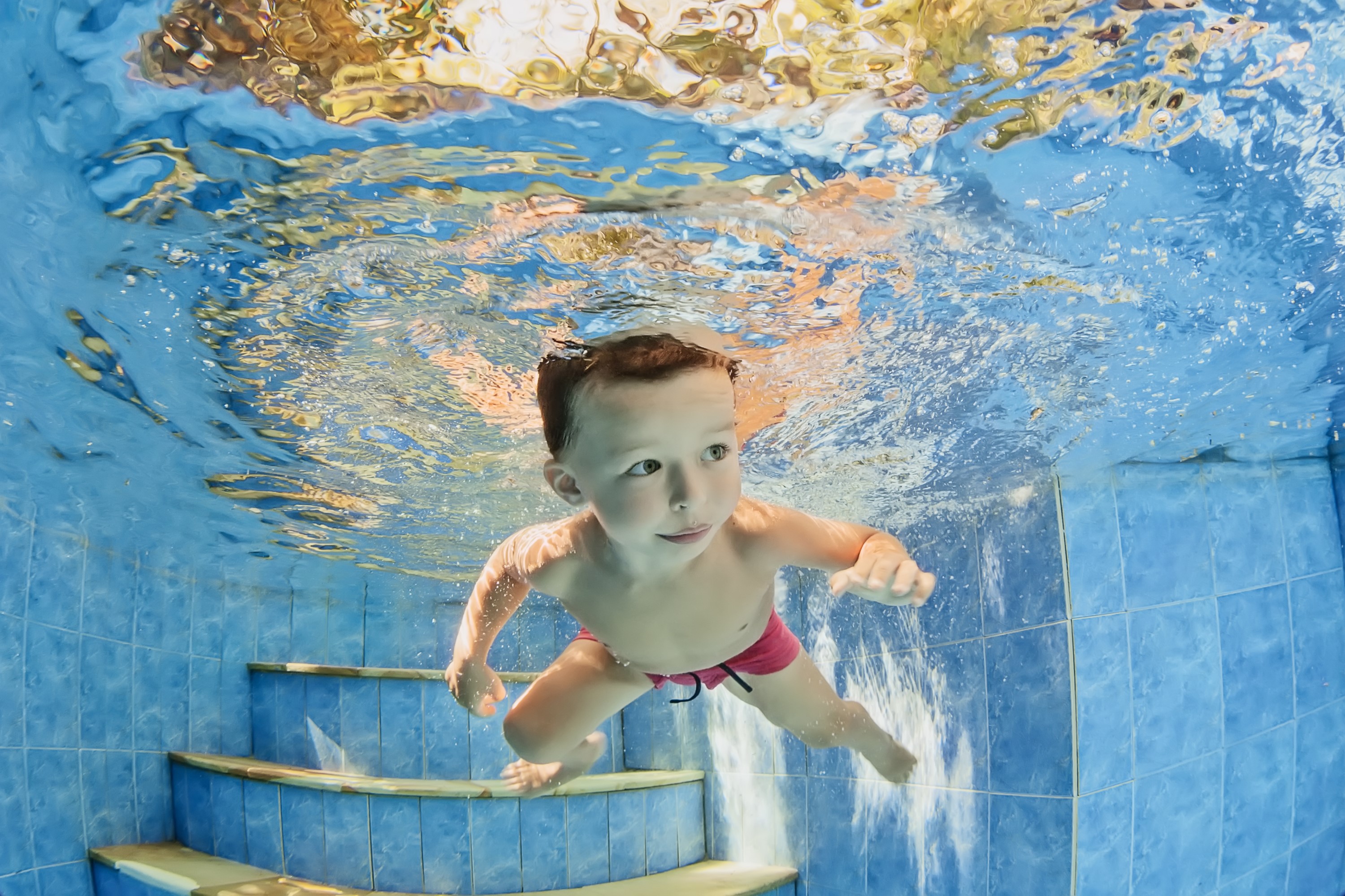 Boy swimming underwater in a pool HD Wallpaper