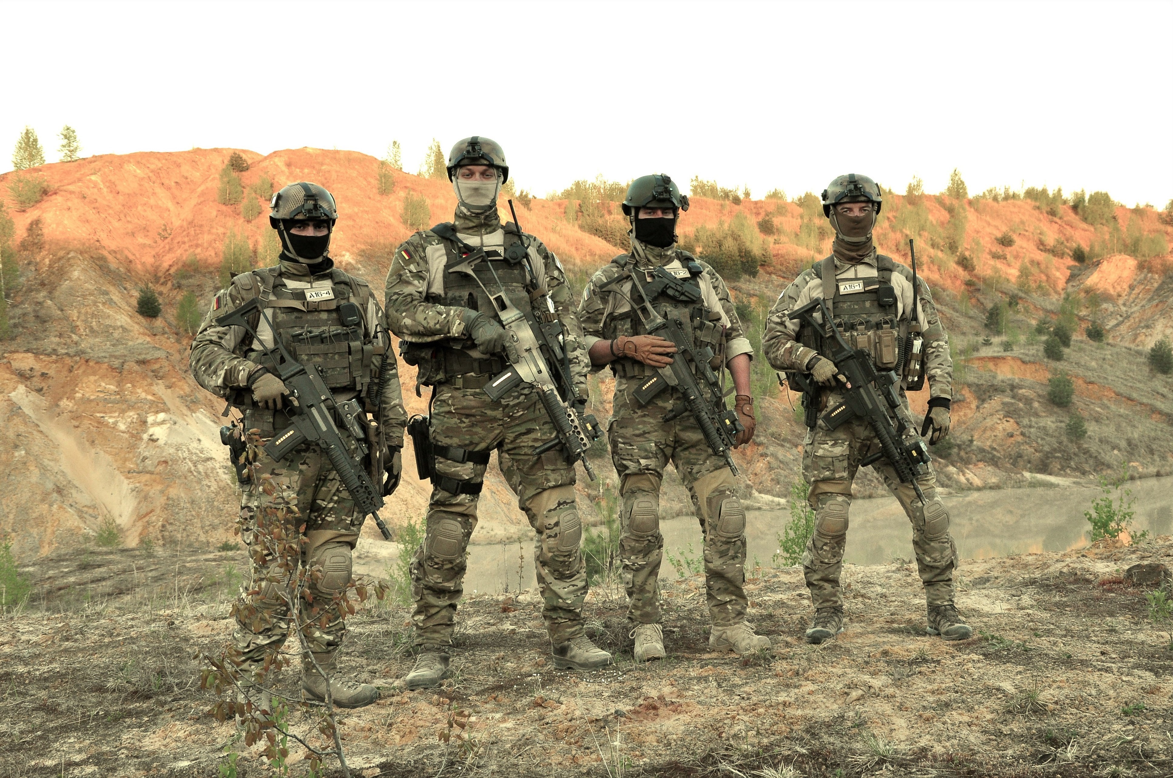 Four soldiers with assault rifles in camouflage HD Wallpaper