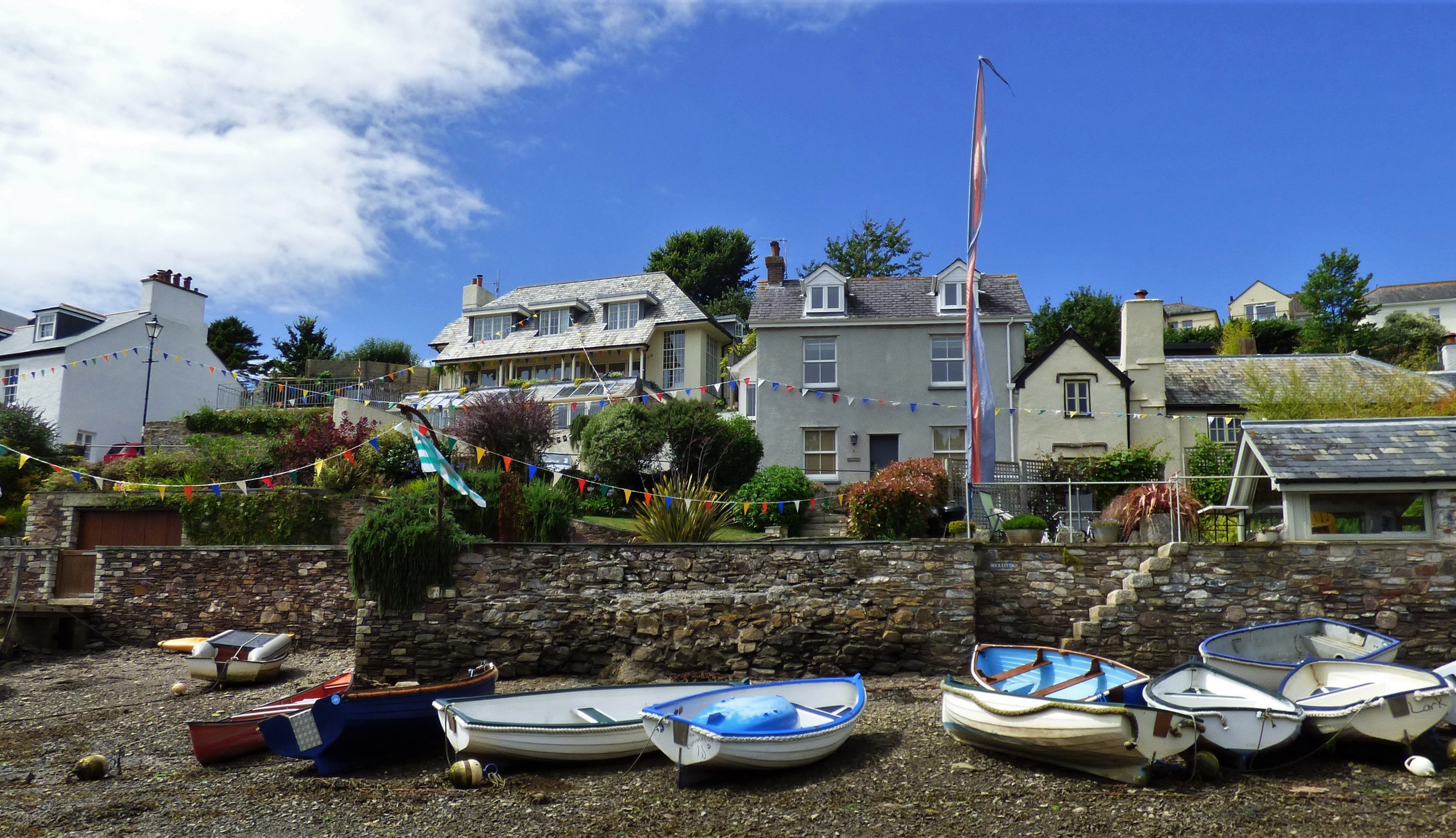 Boats on a pebble beach with houses in the background HD Wallpaper